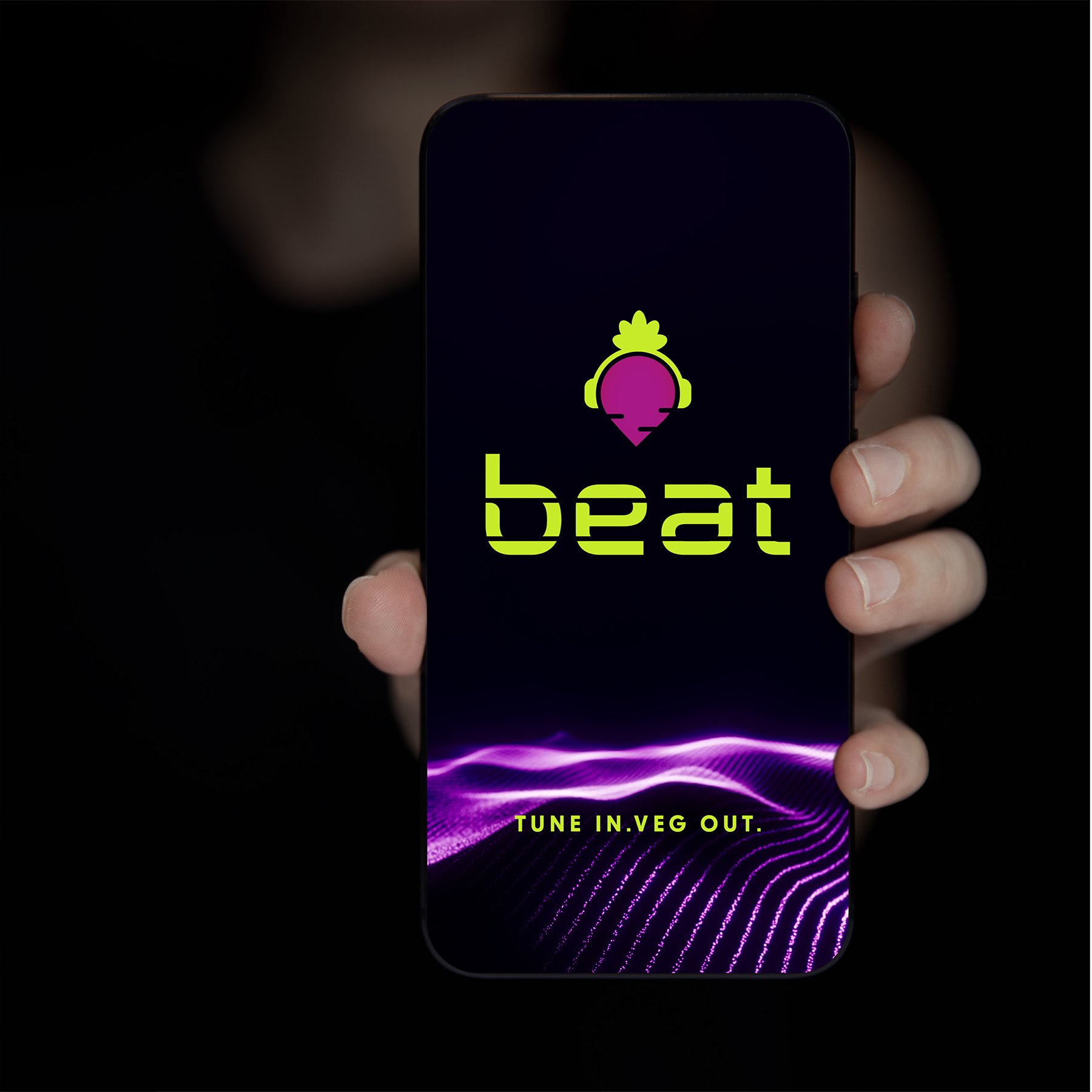 Hand holding smartphone displaying "Beat" app logo with vegetable icon and text "Tune In. Veg Out." against a dark background with purple waves.