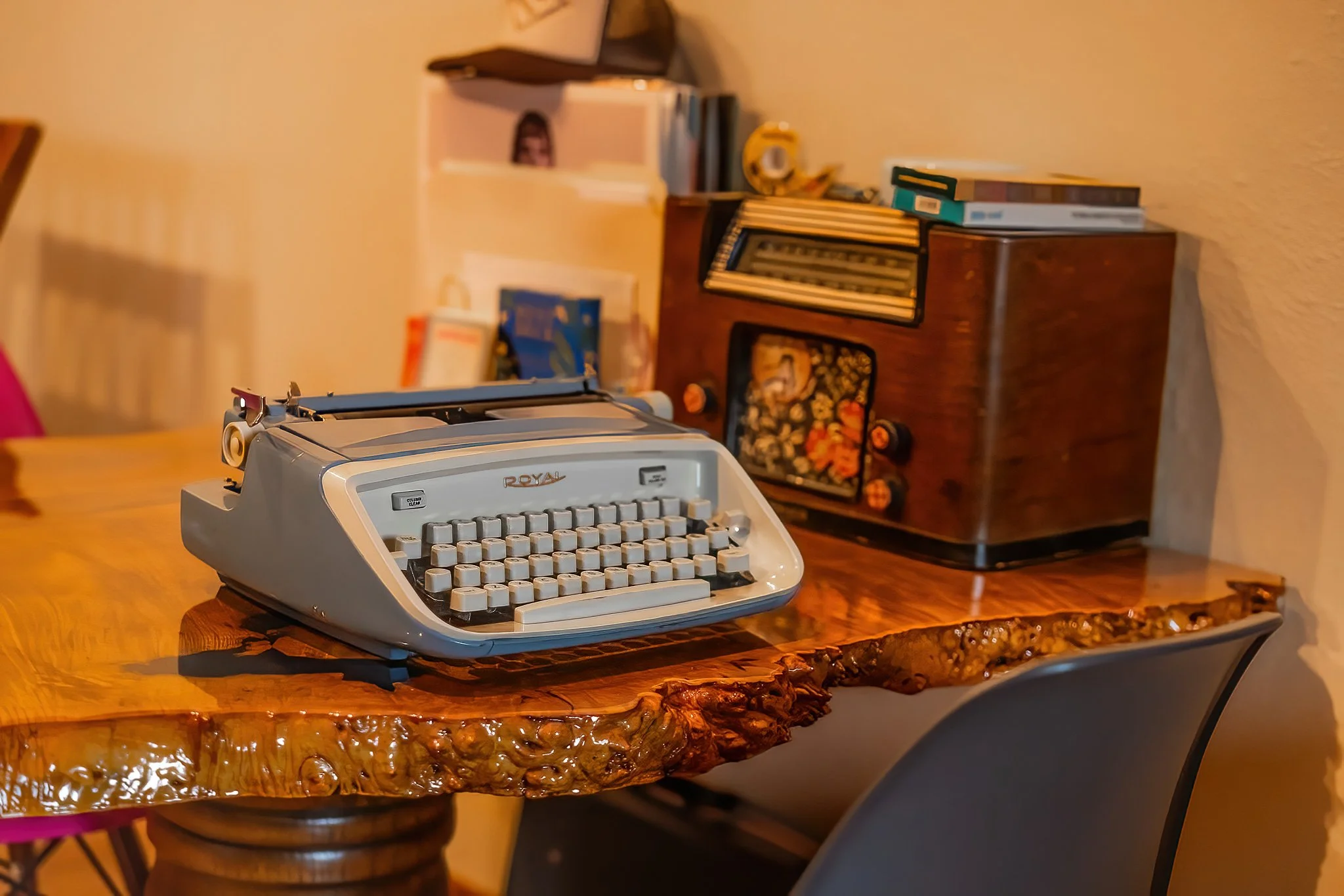 Vintage gray Royal typewriter on a wooden table with a rugged, glossy edge in a cozy room with a mid-century look.
