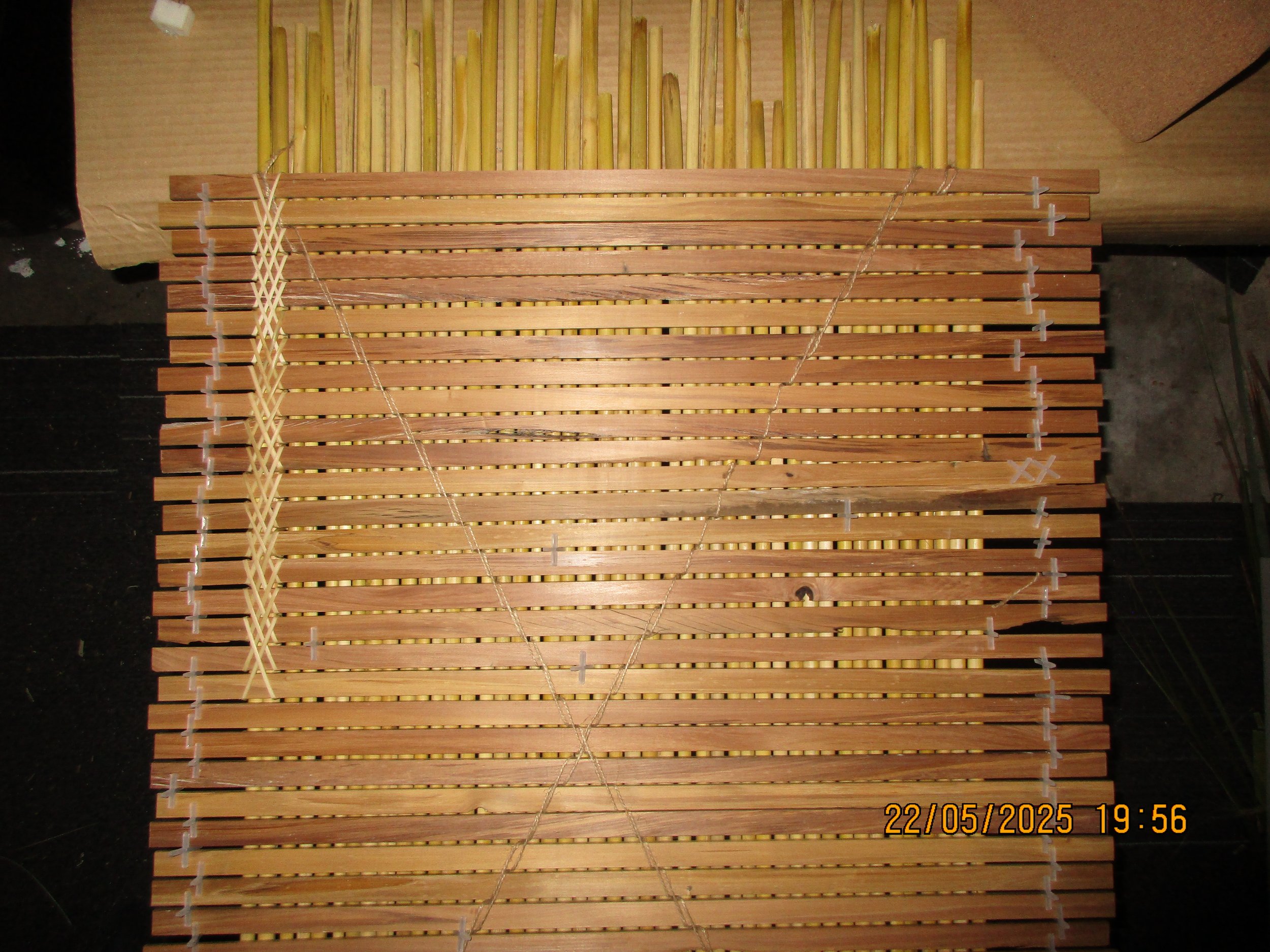 A wooden bed slat frame with some strings stretched across it, placed on a table.