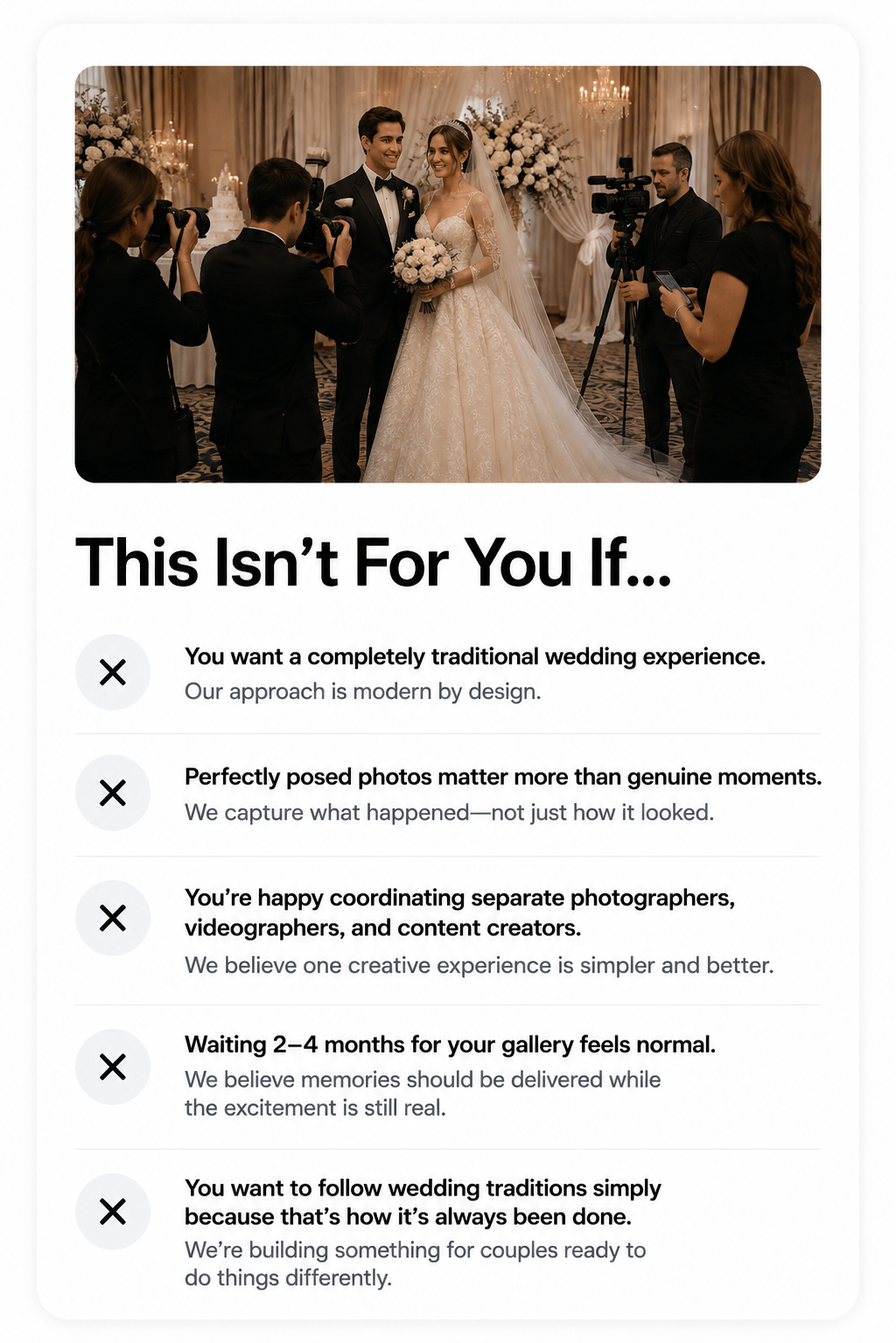 A bride and groom in wedding attire standing and smiling in front of a decorated wedding backdrop with flowers, surrounded by photographers and videographers capturing the moment.