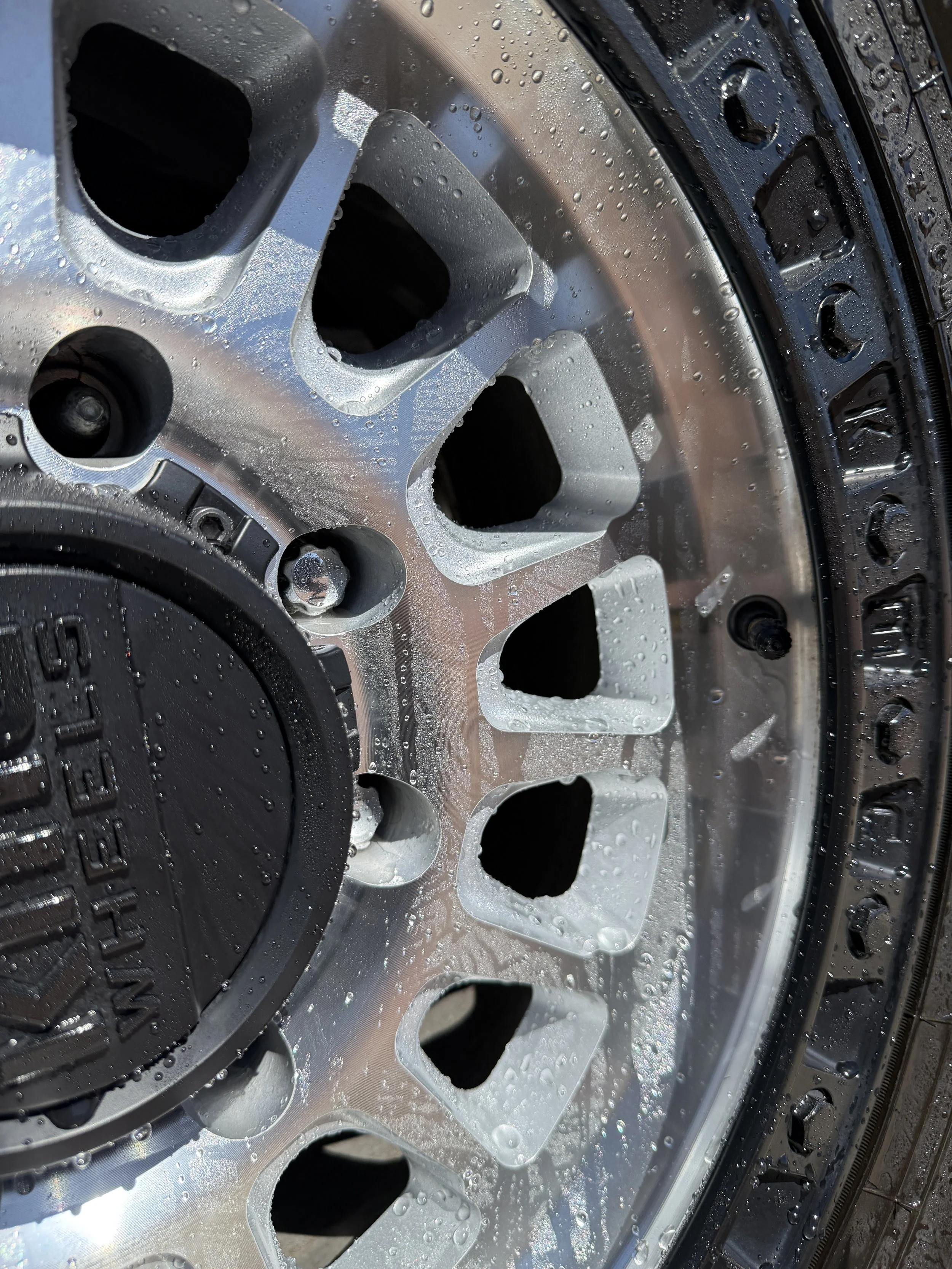Close-up of a wet car wheel rim with water droplets on the surface.