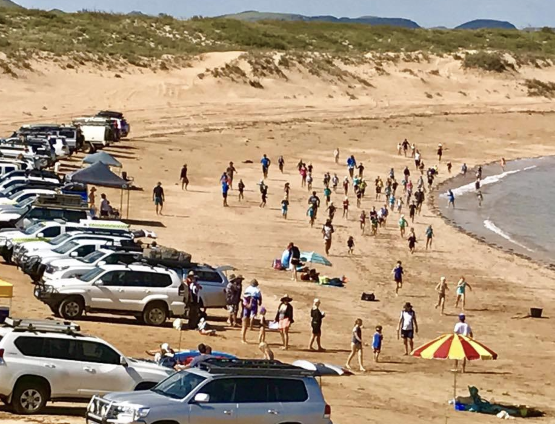 Large group of people assembled on a beach for a competition