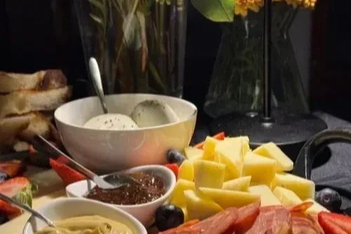 Assorted cheeses, sliced meats, bread, and condiments on a table  as part of a food spread for a private event.