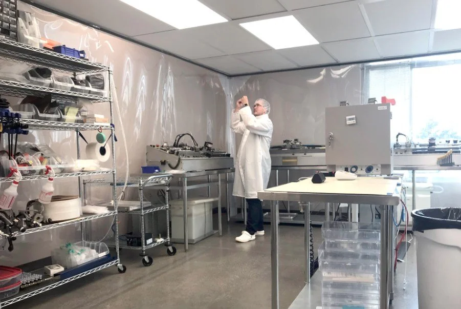 Person in lab coat inspecting sample in laboratory setting