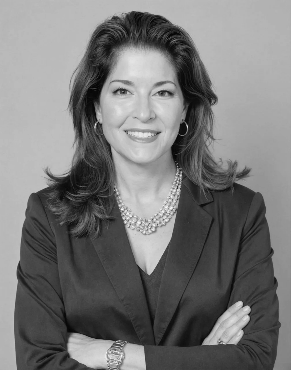 Black and white portrait of a woman smiling with shoulder-length hair wearing hoop earrings.