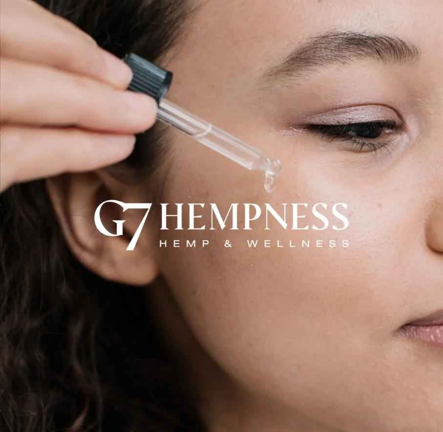 A woman applying a drop of oil or serum to her face using a dropper, with the logo 'G7 Hemppness Hemp & Wellness' overlaid on the image.