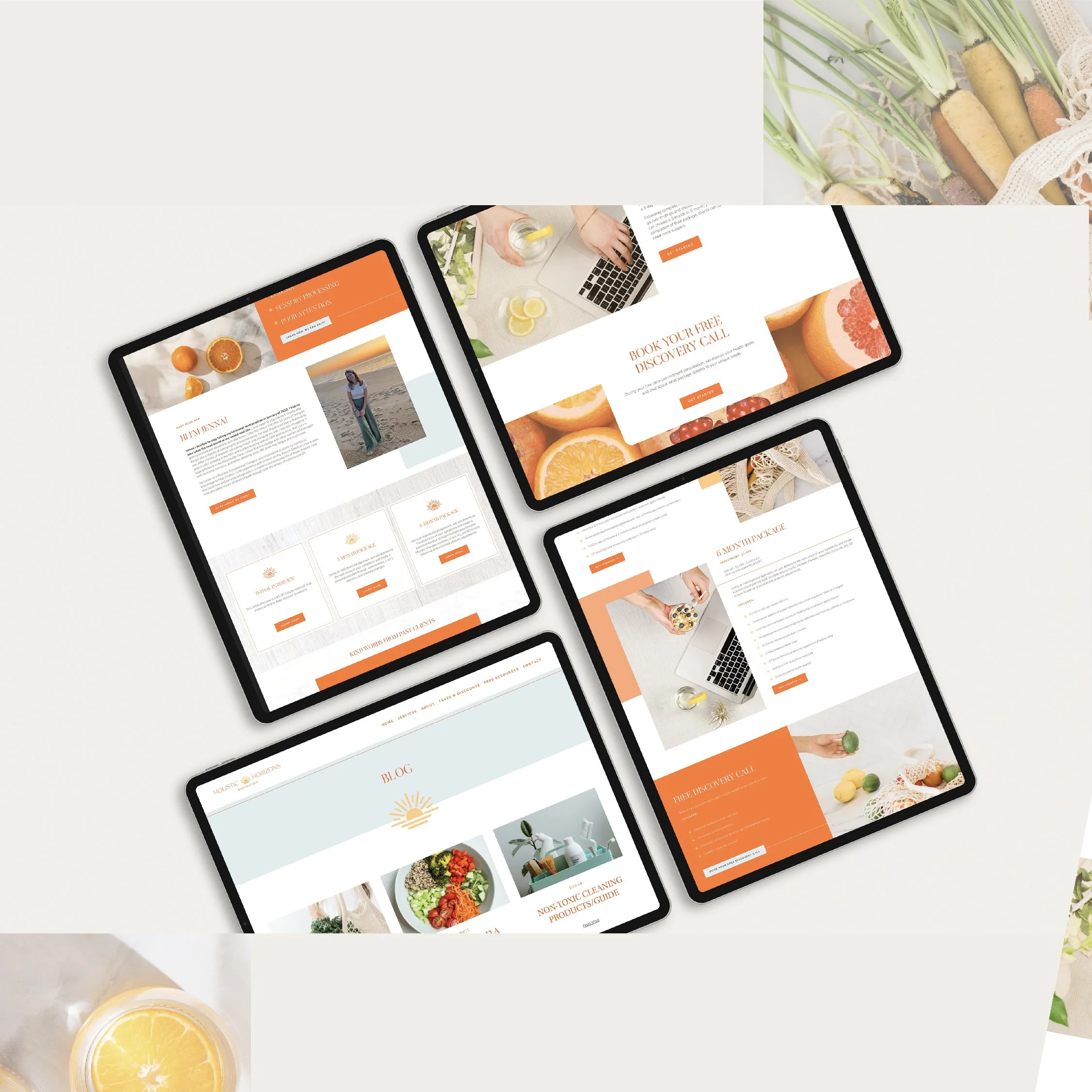 Flat lay of four tablets displaying website designs with orange and white themes, surrounded by lemons, oranges, and vegetables on a white surface.