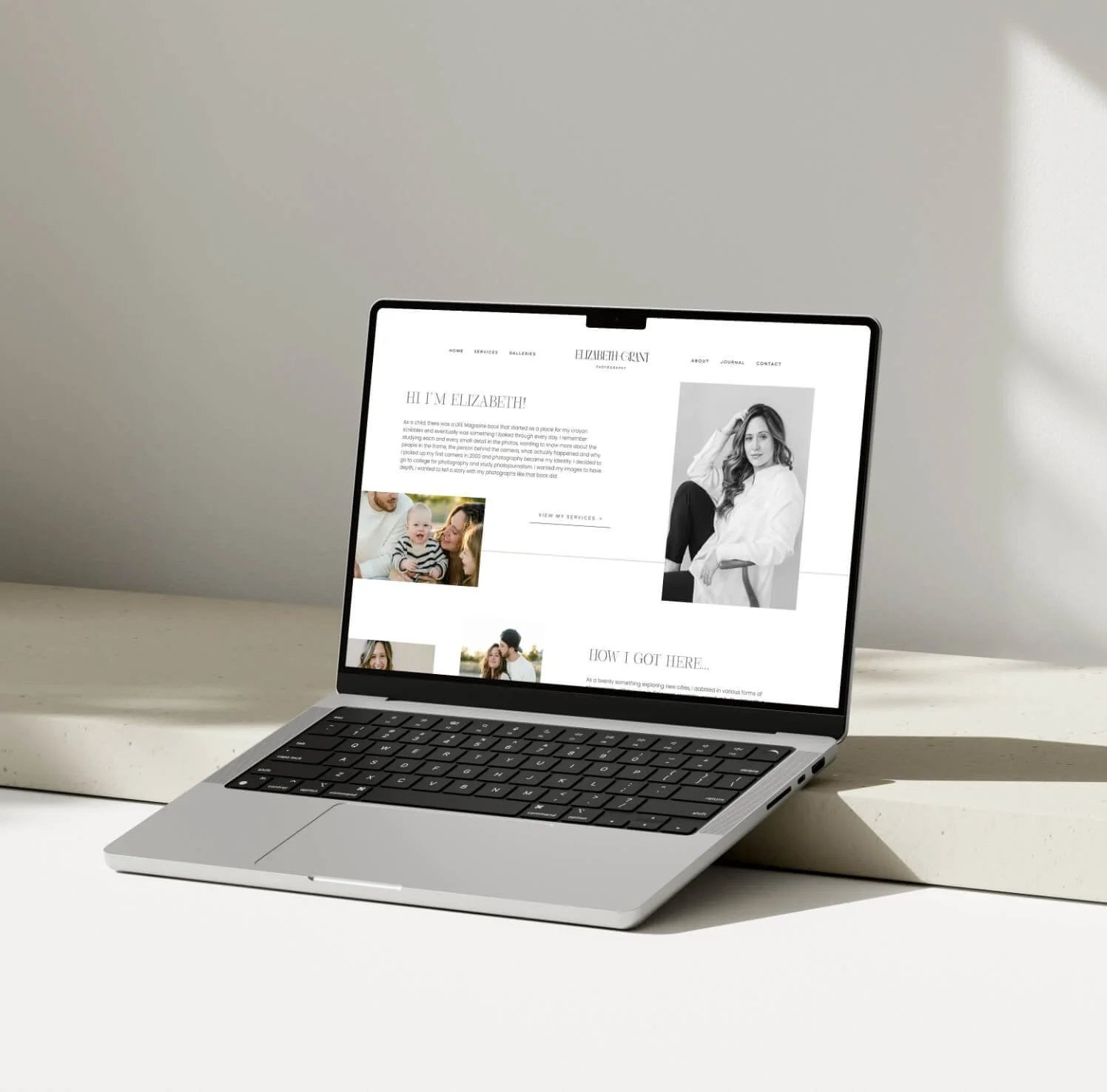 Open laptop displaying a photography website with a black and white portrait of a woman, some photos of a family, and text about the photographer.