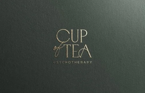 Close-up of a dark green box with gold lettering that reads "Cup of Tea Psychotherapy."