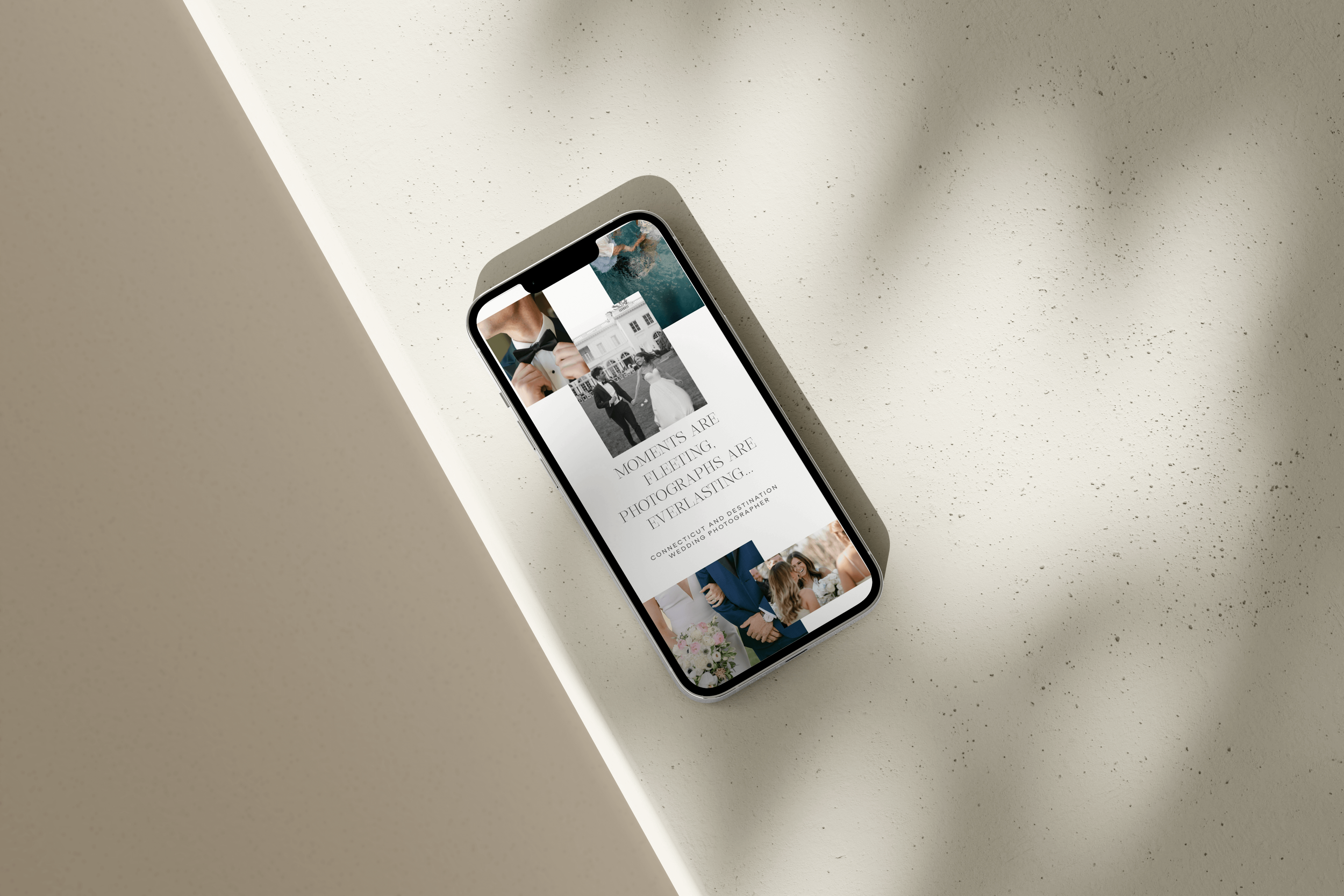 Smartphone displaying a wedding photography website on a minimalist beige table.
