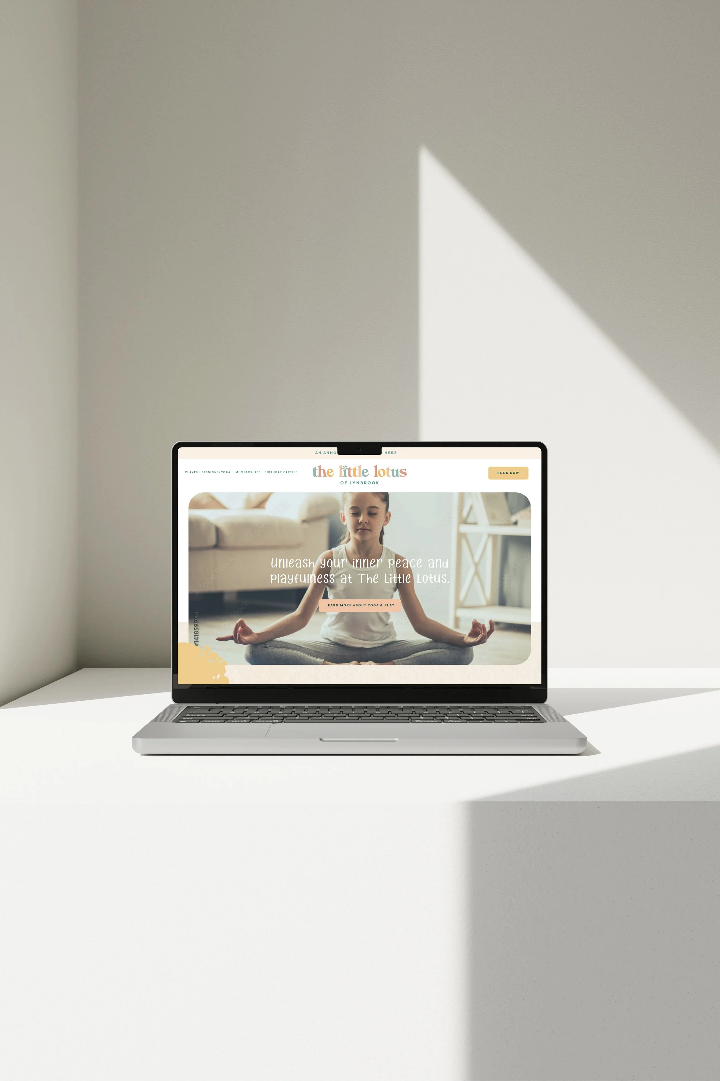 Laptop on white table displaying a yoga website with a woman meditating in a bright room.