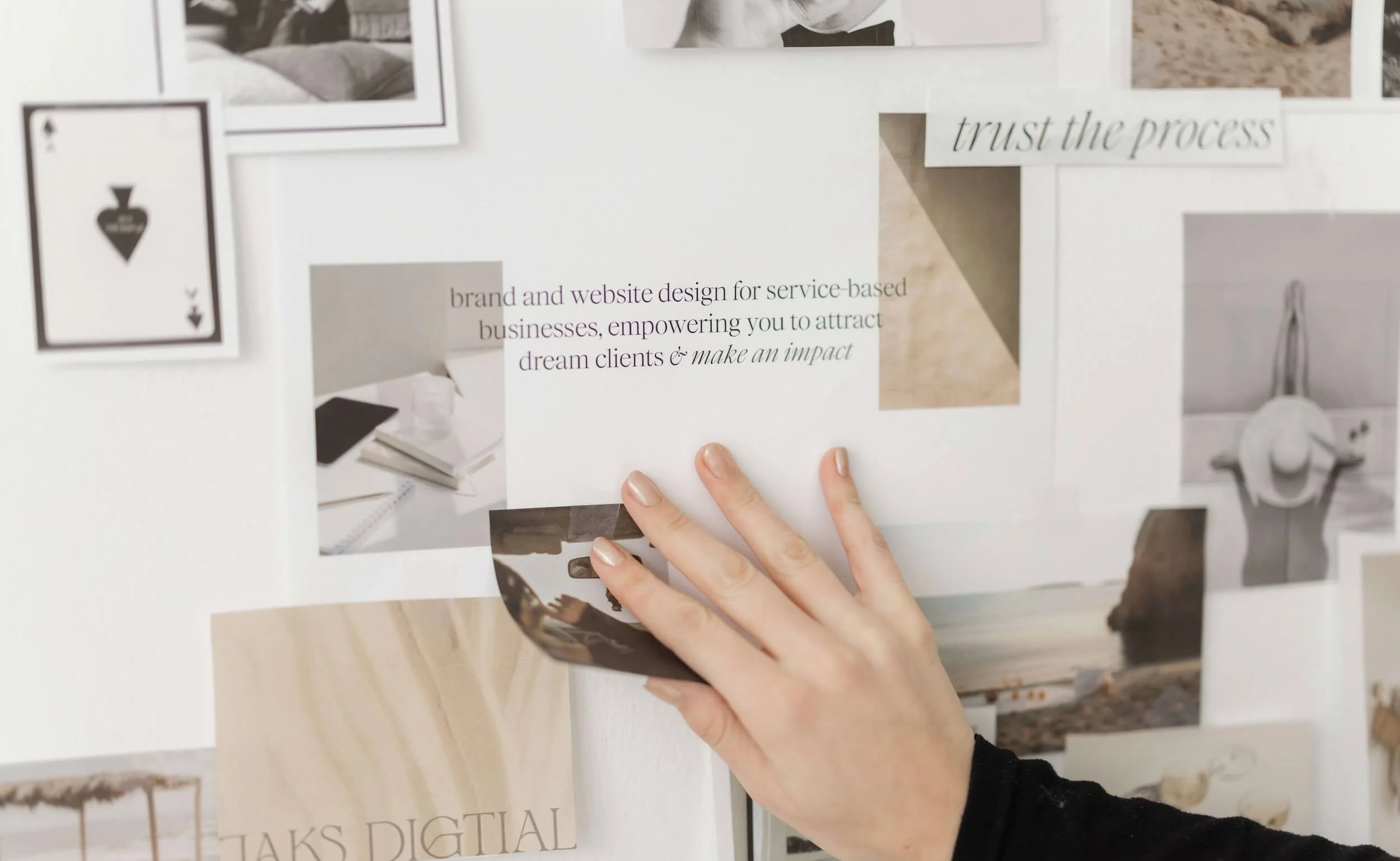 Close-up of a hand pinning a photo to a collage wall with various photos and text, including 'trust the process' and a message about brand and website design.