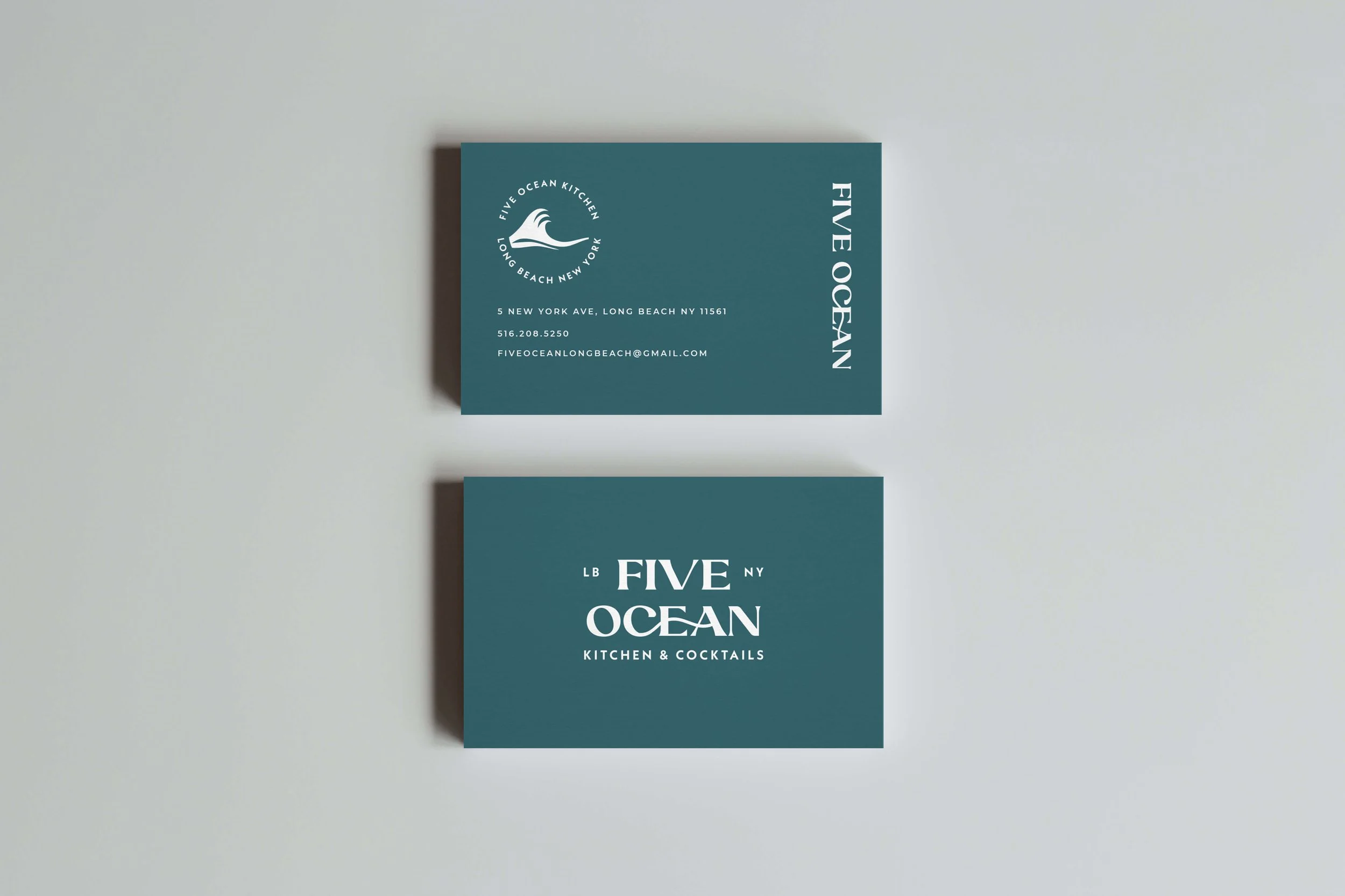 Two business cards for Five Ocean Kitchen & Cocktails on a white surface, one showing contact details and the other displaying the restaurant's logo and name.
