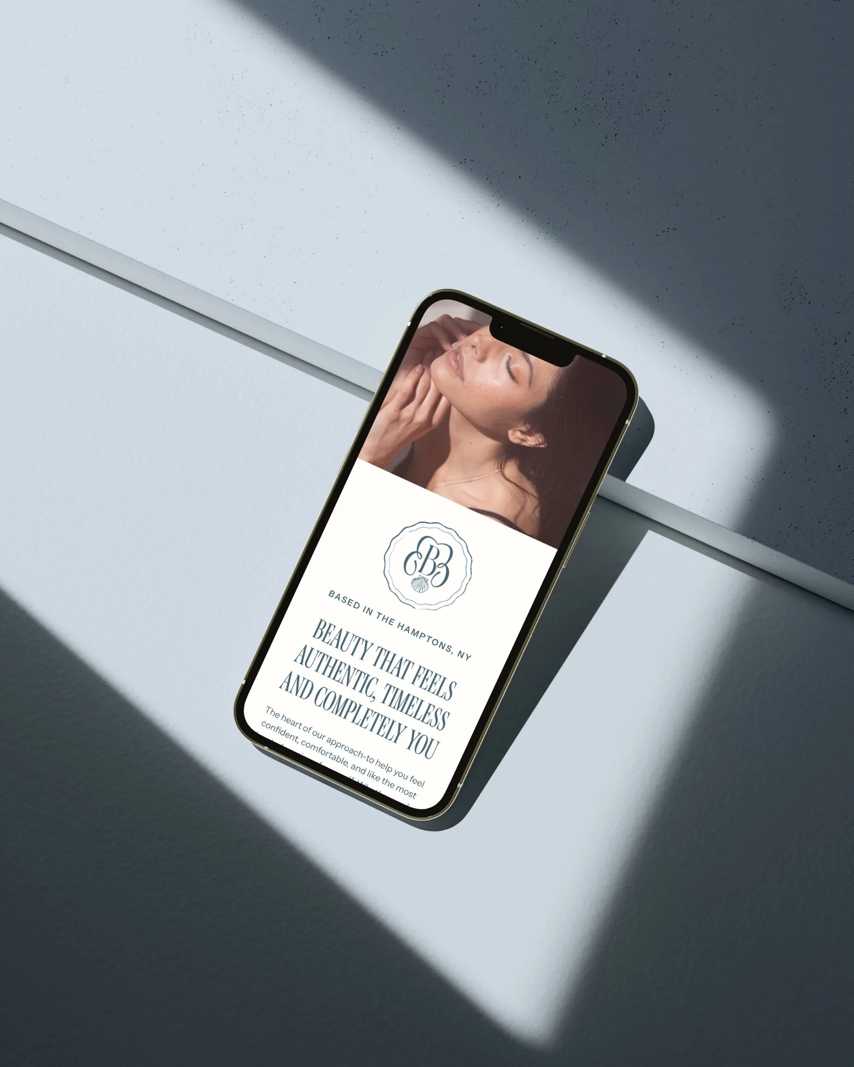 Smartphone displaying a beauty salon website with an image of a woman with long hair and glowing skin, under natural light and shadows.