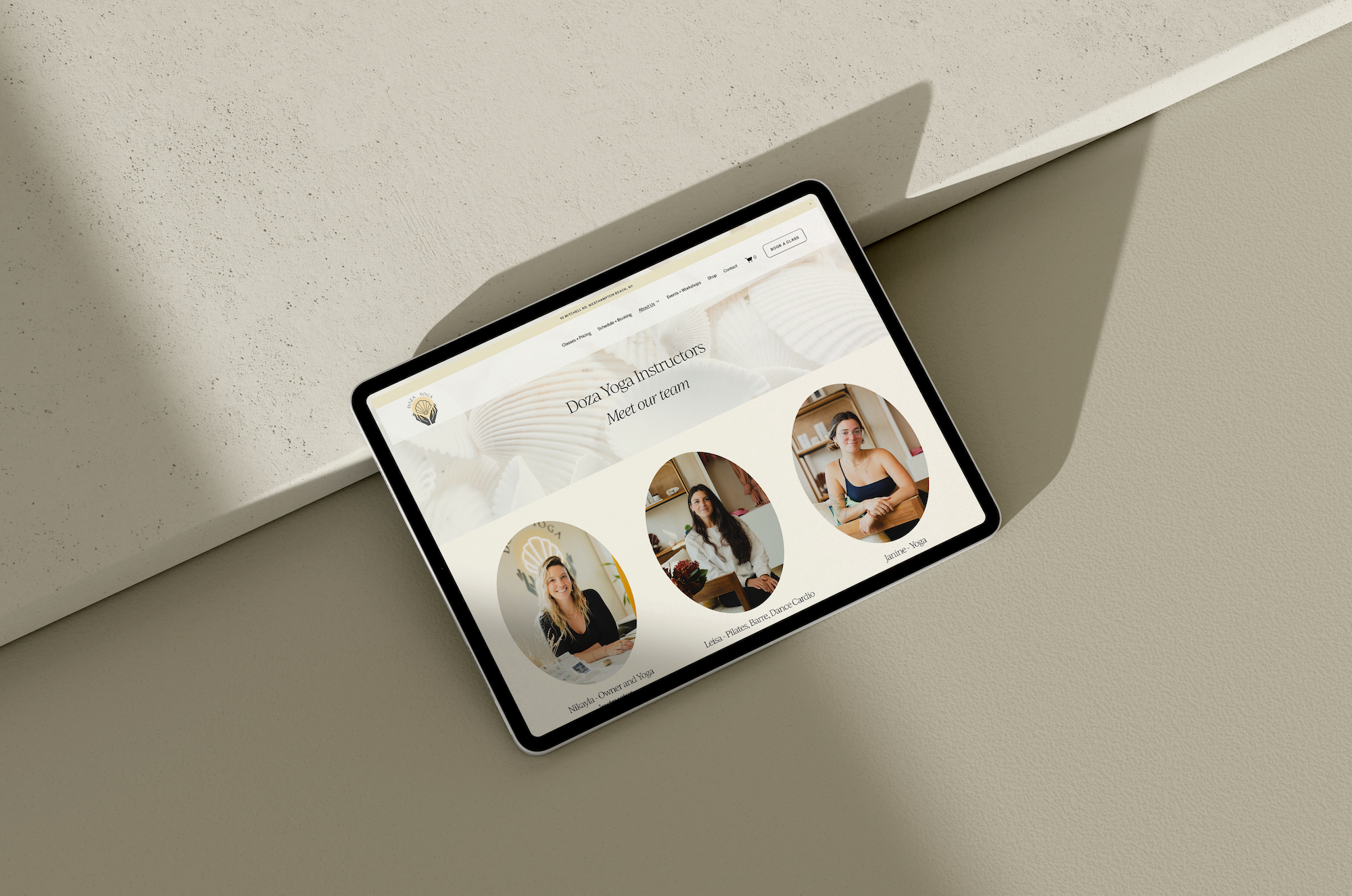 A tablet on a textured beige surface displaying a website with the heading "Doza Yoga Instructors Meet our team" and photos of three yoga instructors.
