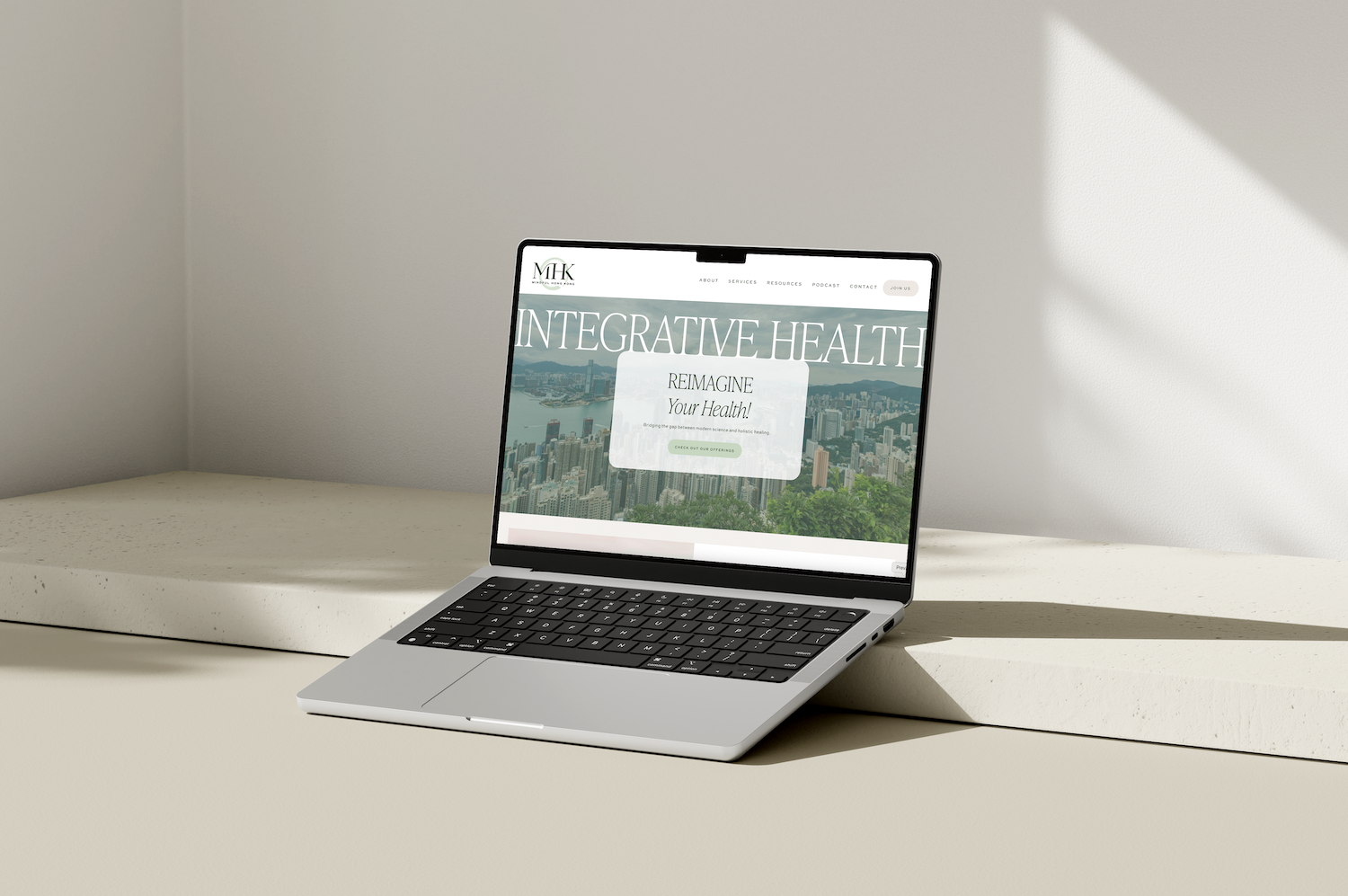 Open laptop displaying a website about integrative health on a white surface with a plain wall background.