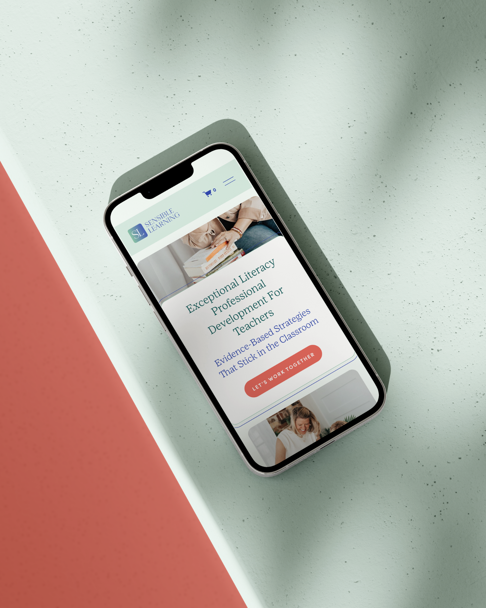 Smartphone displaying a website for Sensible Learning with information about literacy professional development for teachers, on a textured surface with pink and gray sections.