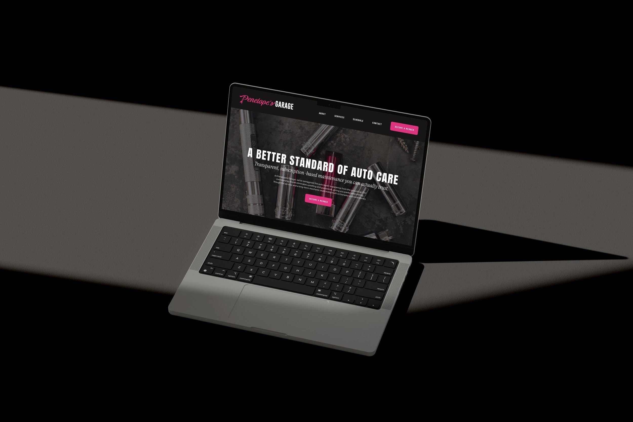 Open laptop displaying Penelope's Garage website with a dark background and pink accents, featuring auto care tools and text