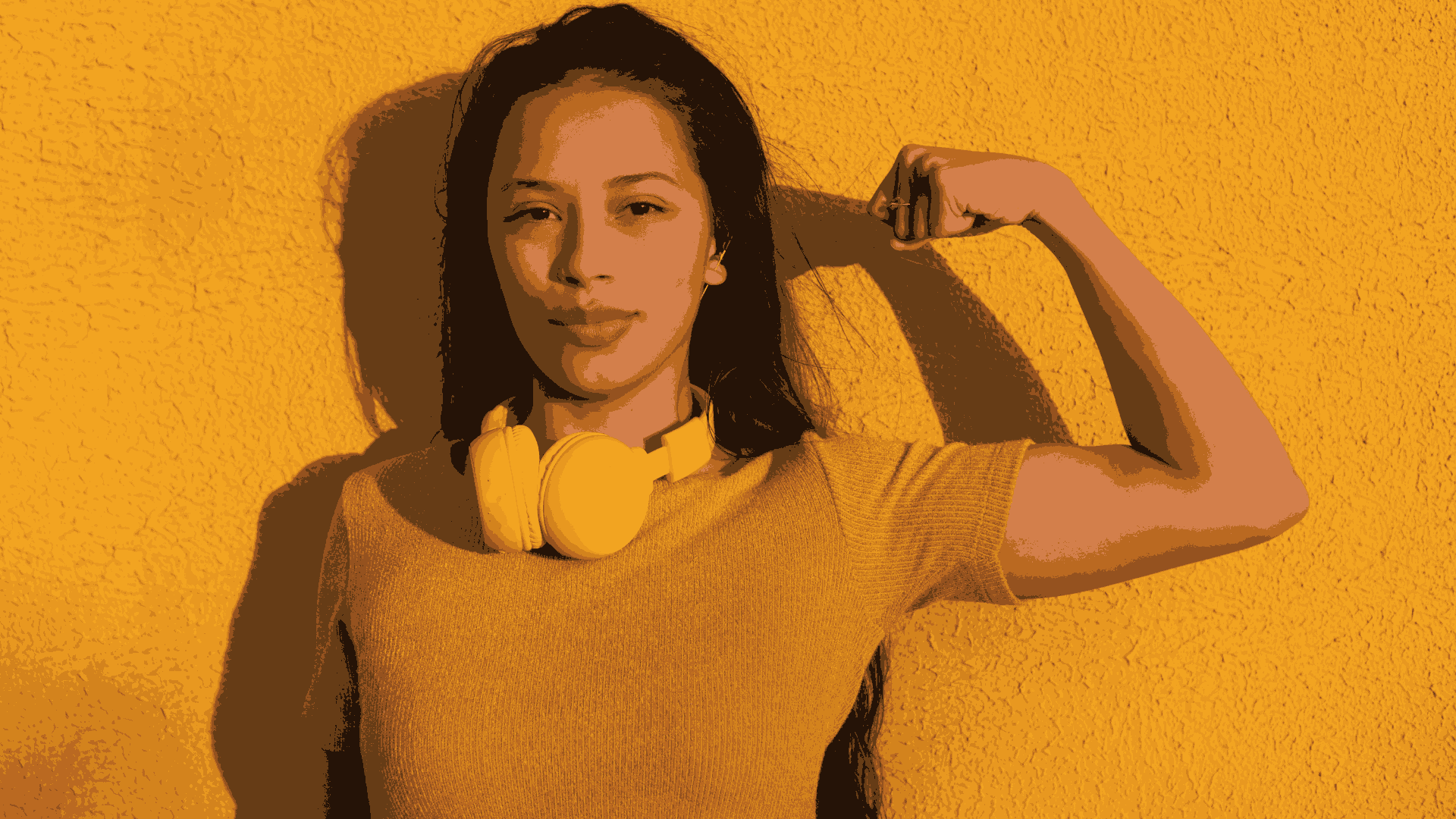 Woman in front of a yellow background flexing her bicep
