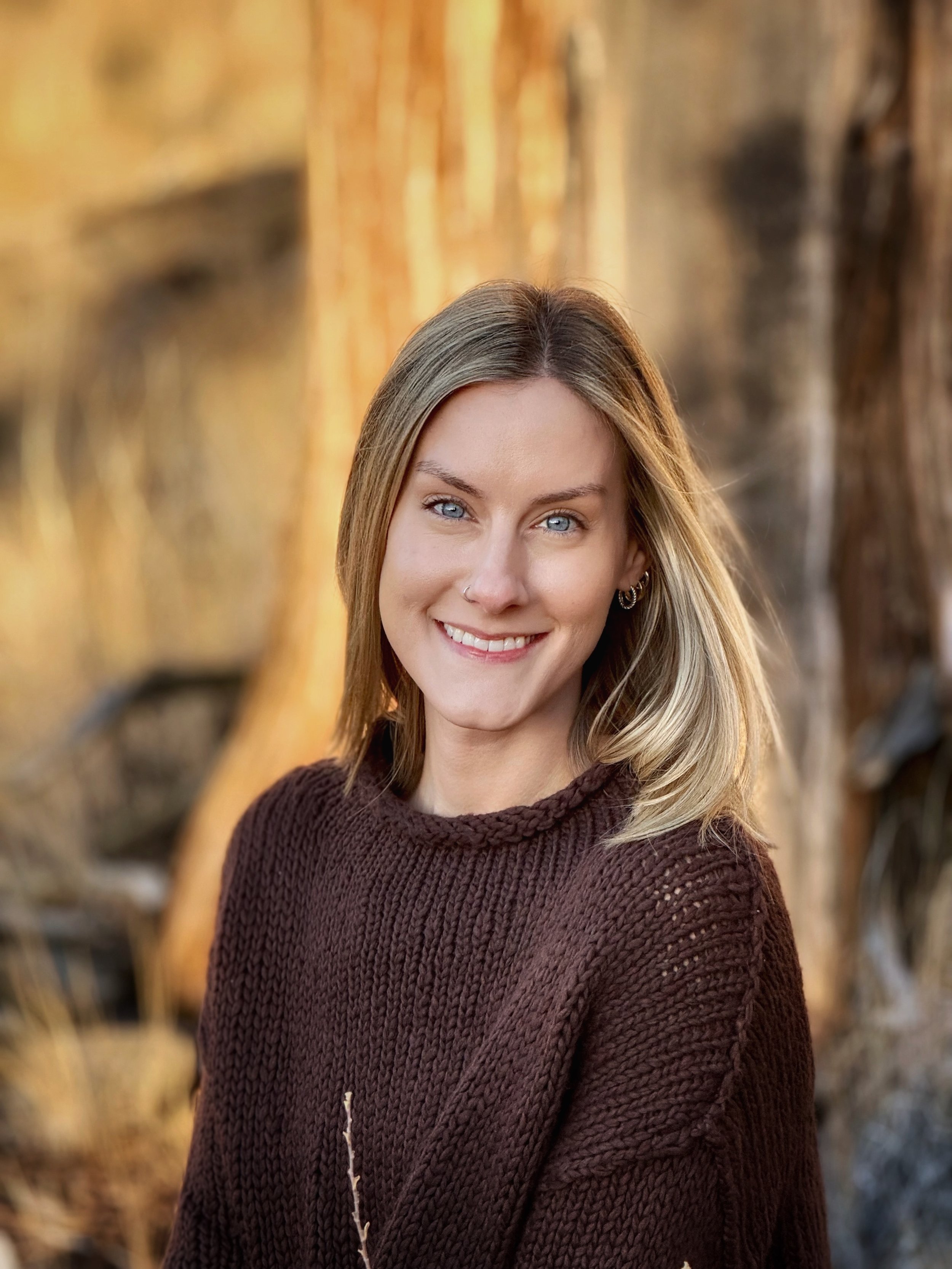 Headshot of a blonde woman in a brown sweater