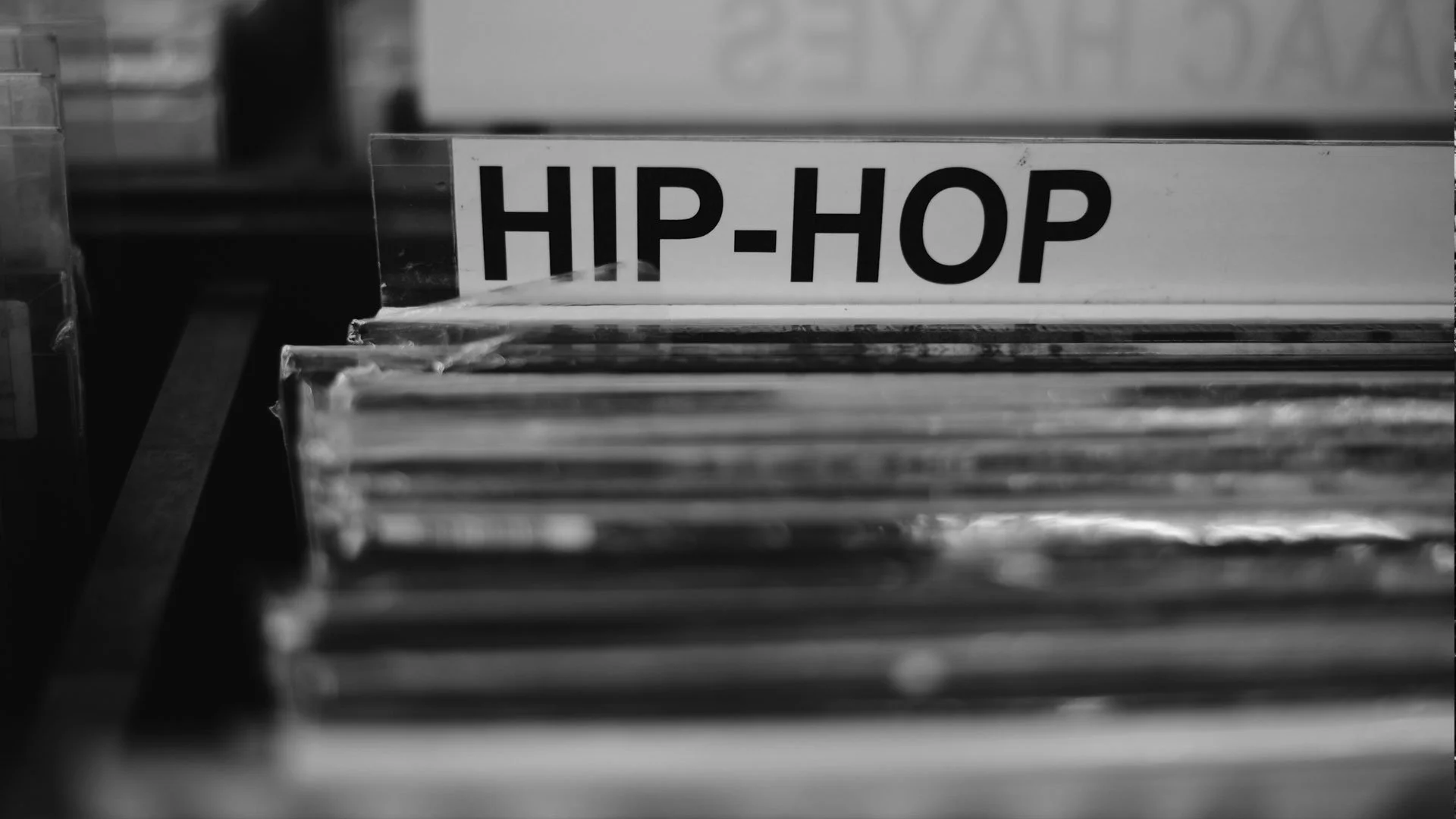 Black and white photo of a vinyl record section labeled 'HIP-HOP' on a store shelf.