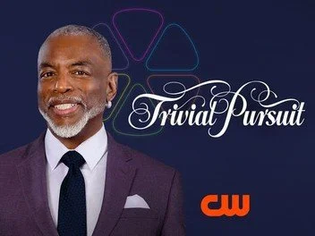 TV show poster with a man in a suit smiling in front of a "Trivial Pursuit" logo and "CW" network branding.