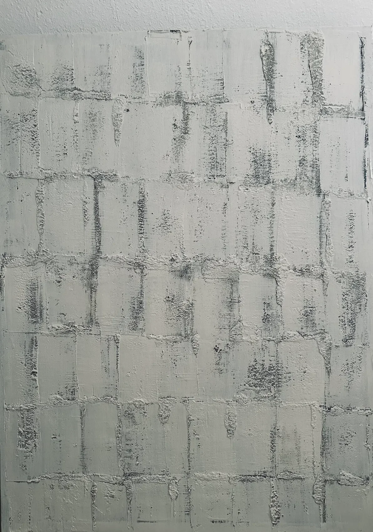 Close-up of a white painted brick wall with rough textures and grayish mortar lines.