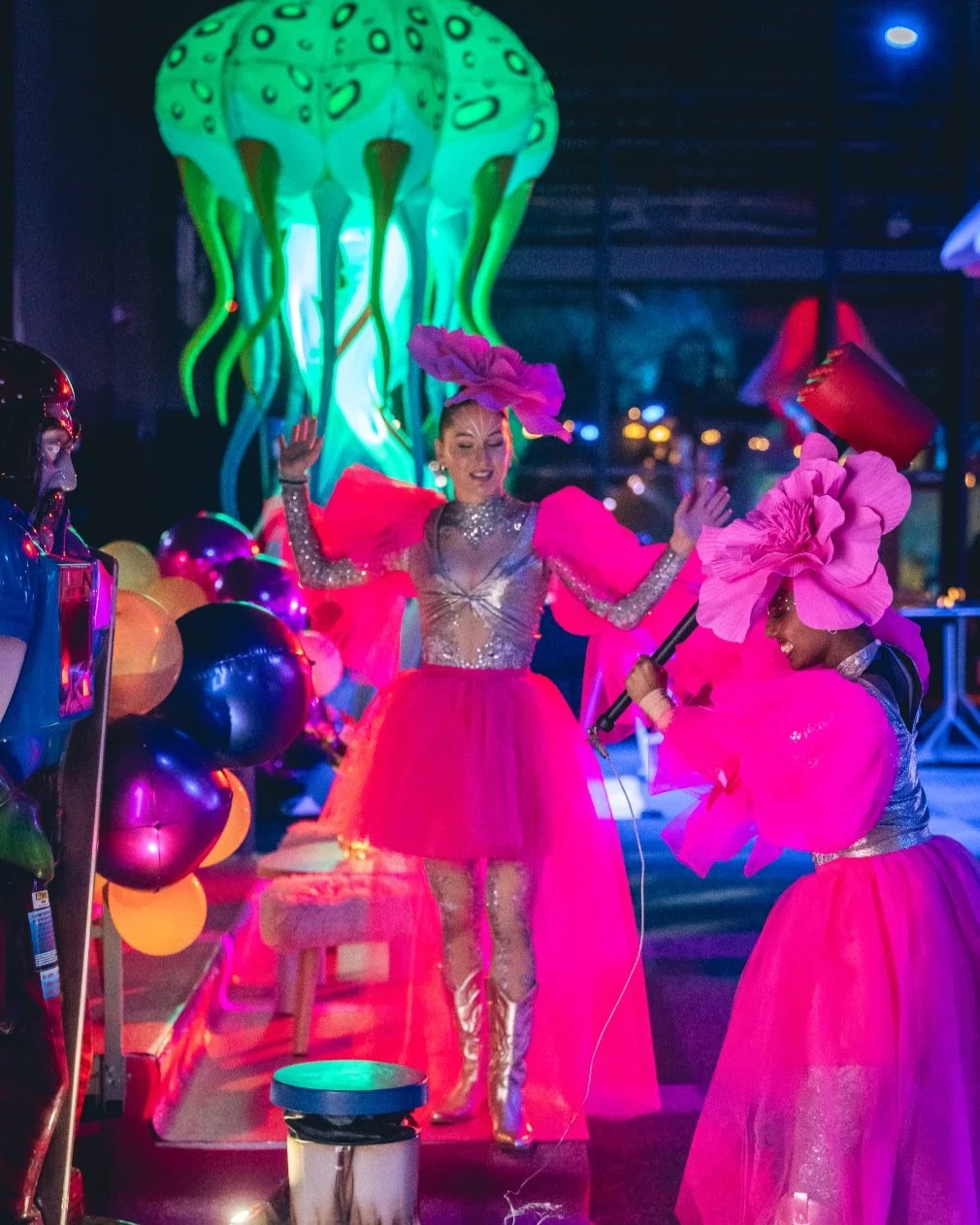 Two females in pink beautiful outfits playing games in a party environment.