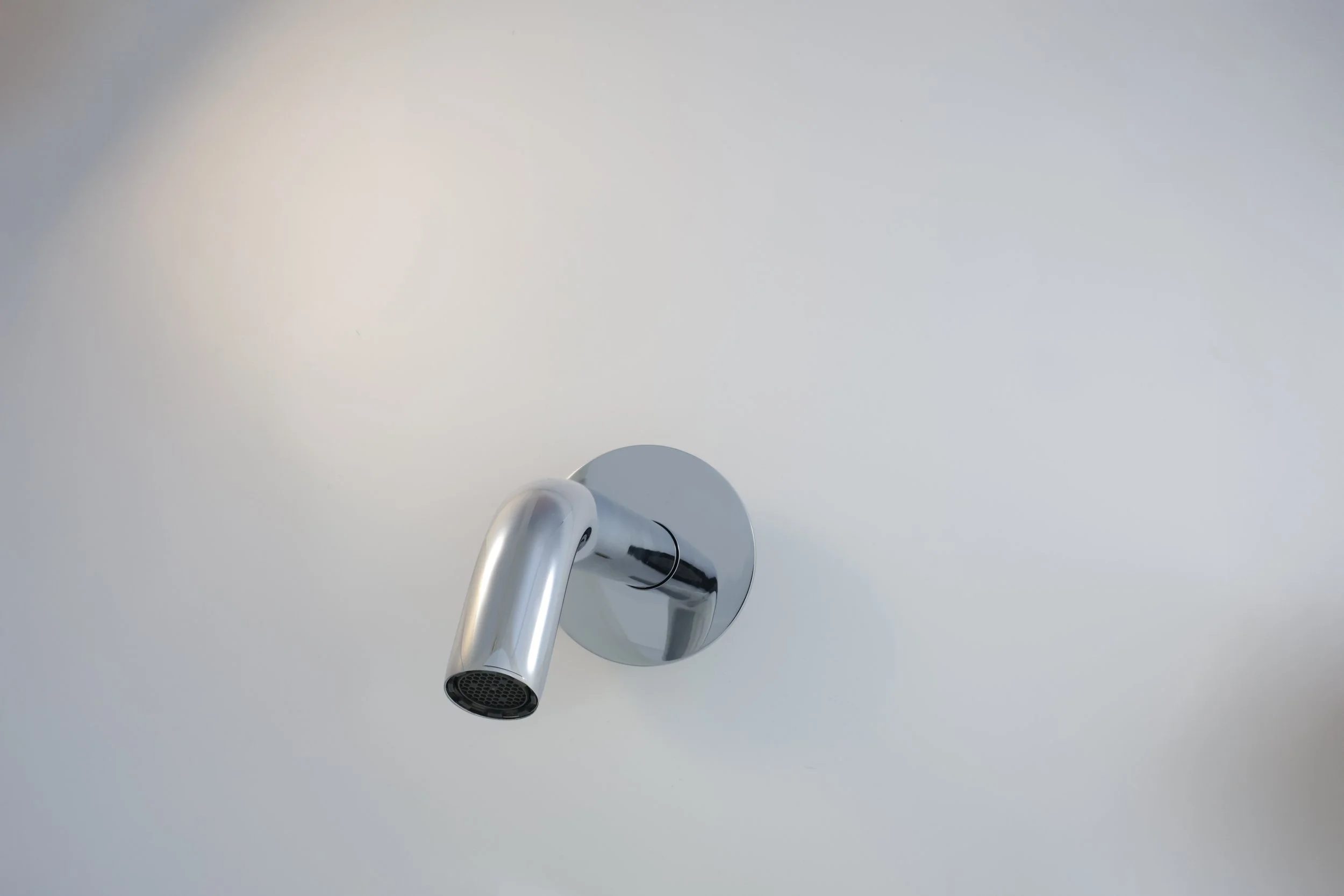 Chuveiro de parede de metal cromado instalado em uma parede branca