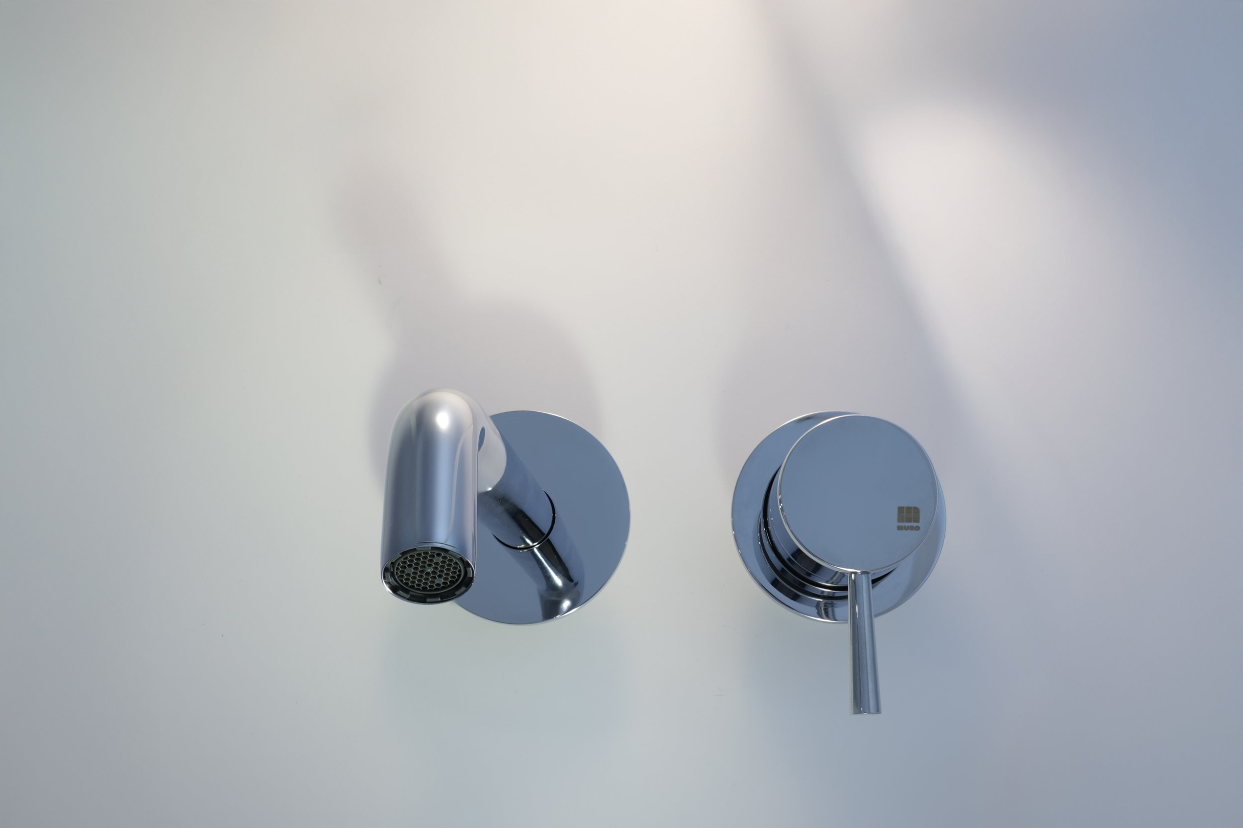 Duas luminárias de teto modernas, uma com formato de tubo e outra como uma esfera, ambas com acabamento metálico prateado, instaladas em um teto branco.