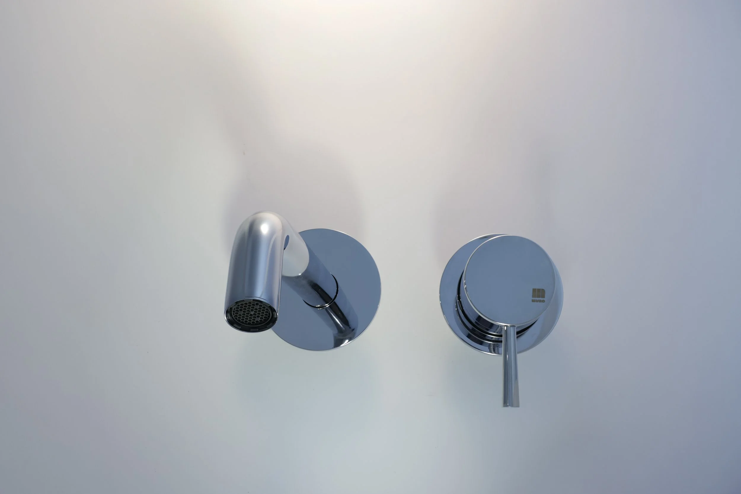 Tampa de registro de água prateada com detalhes brilhantes, instalada em um teto branco.