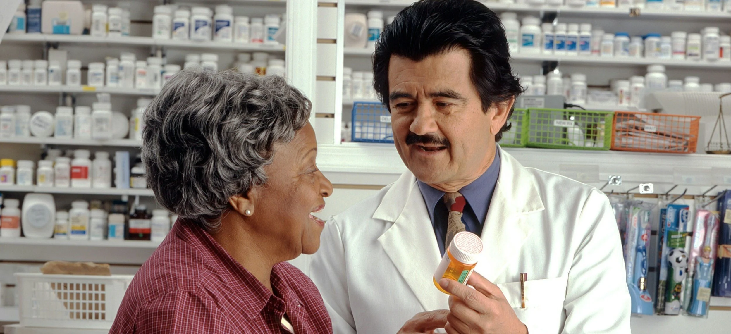 A pharmacist showing medication to an elderly woman in a pharmacy.