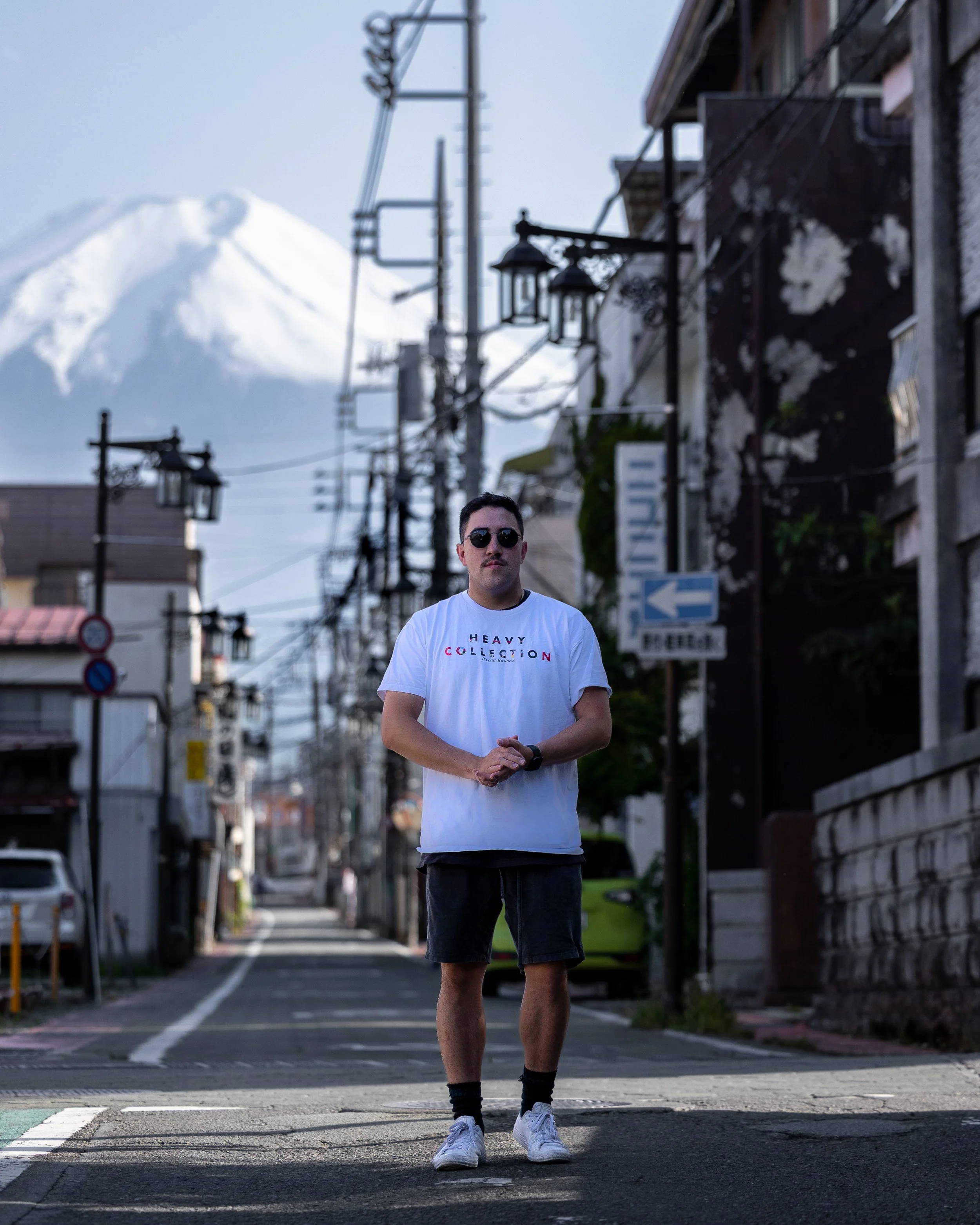 Man in a white shirt standing on a street with a mountain in the background.