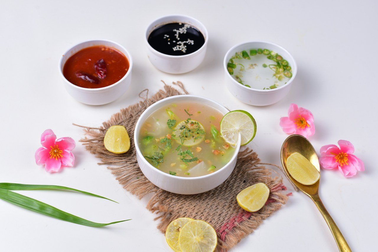 bowls of broth and sauces with lime and flowers
