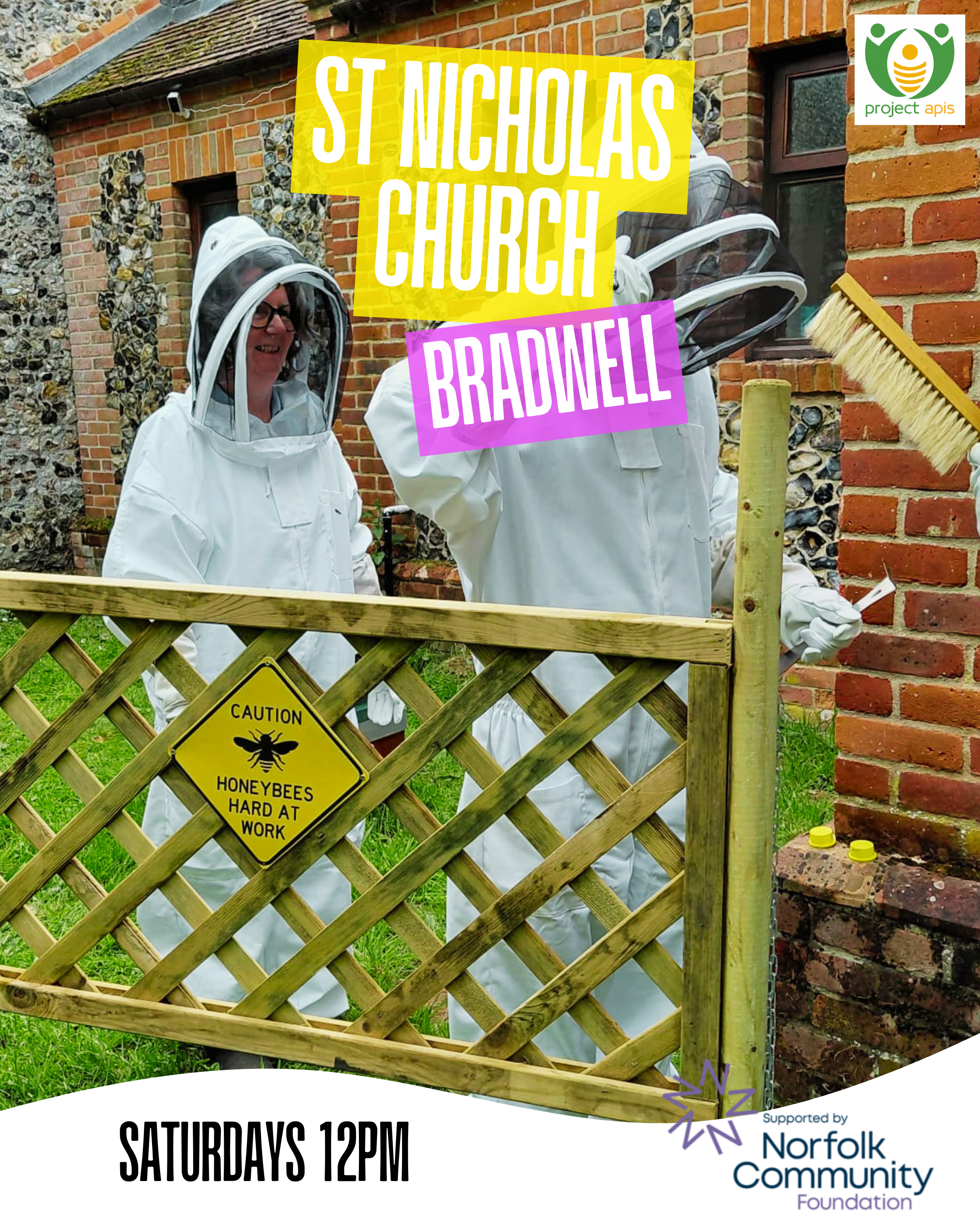 A woman wearing a beekeeping suit and helmet smiling, standing behind a wooden fence with a yellow caution sign that says "HONEYBEES HARD AT WORK." There are small yellow containers on the ground. The background shows a brick and flint house with two small windows, and an outdoor area with grass.
