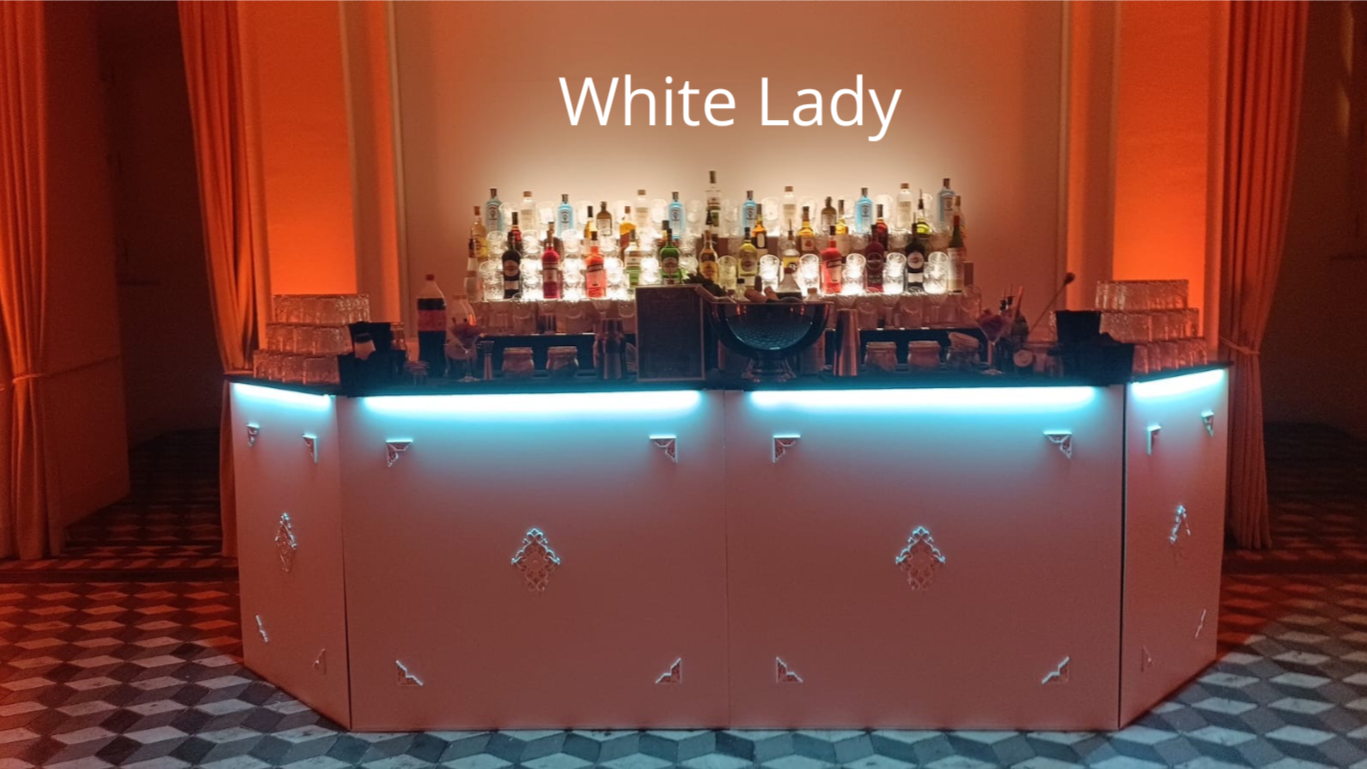 Bar elegante con variedad de botellas de licor y cristalería, con señalización que dice 'White Lady', luces de neón azul y cortinas doradas en el fondo.