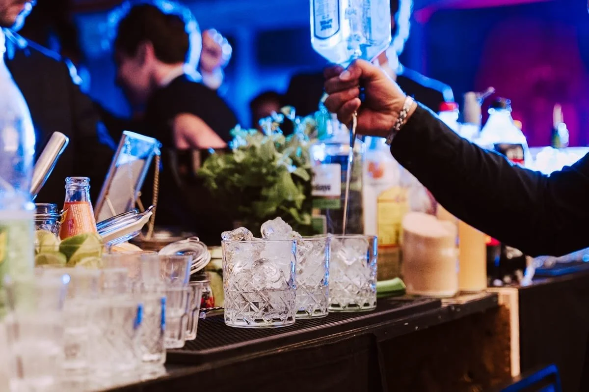 persona preparando cocteles con hielo en un bar en un ambiente con luces de colores