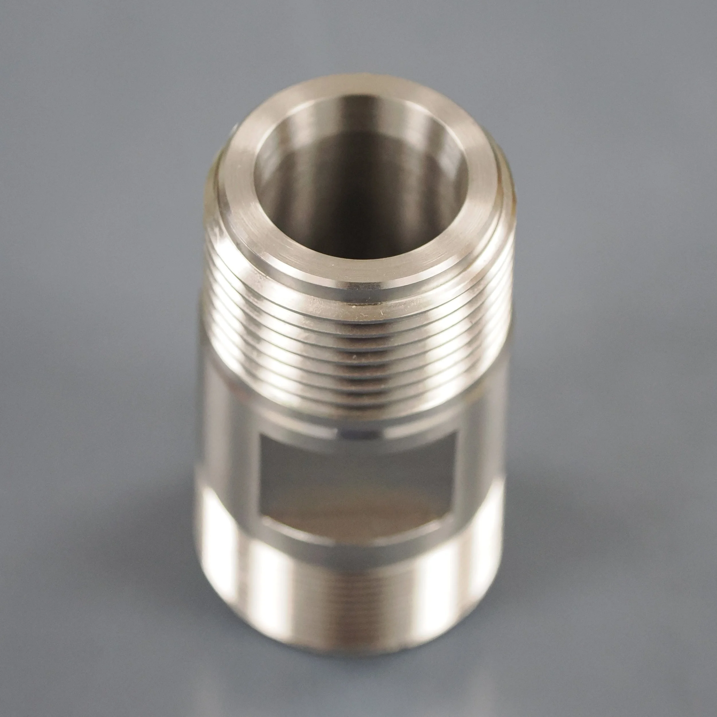 Close-up of a metallic threaded component, possibly part of a machine or tool, with a smooth, shiny surface and a hollow center.