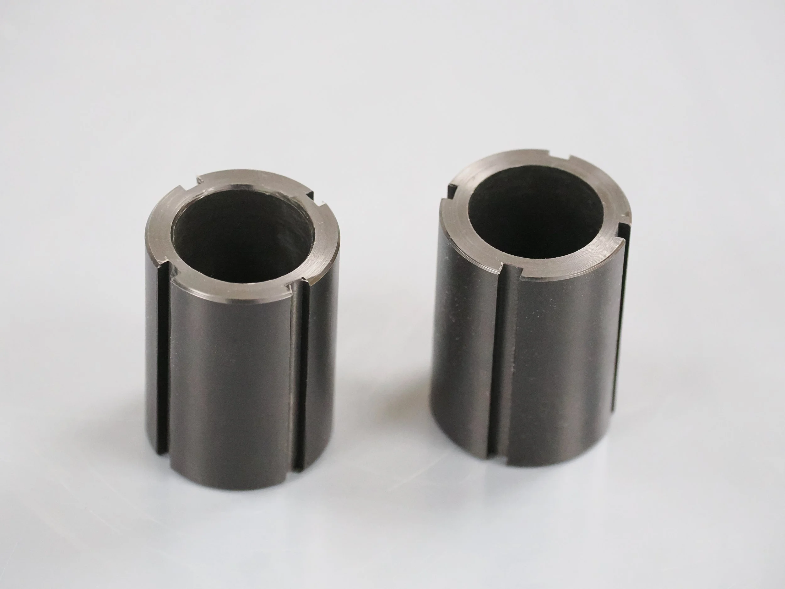 Two metallic hollow cylindrical metal tubes standing upright on a flat surface with a plain white background.