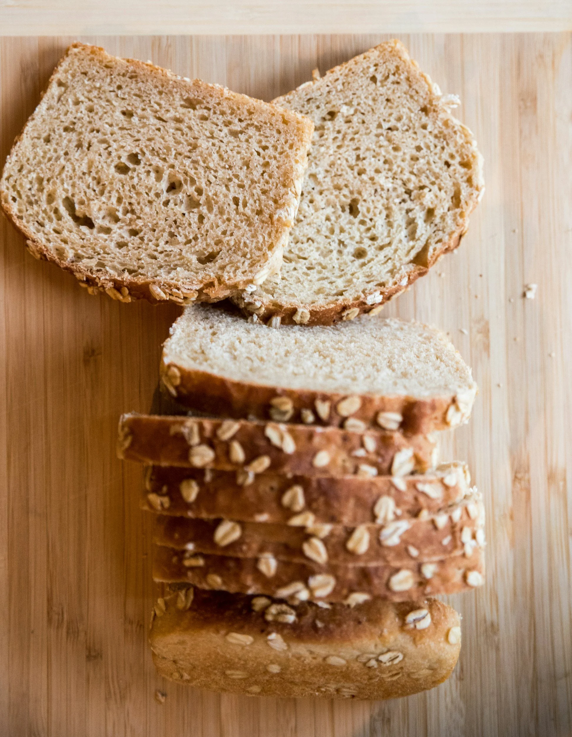 Sliced whole grain multigrain bread on a wooden cutting board.