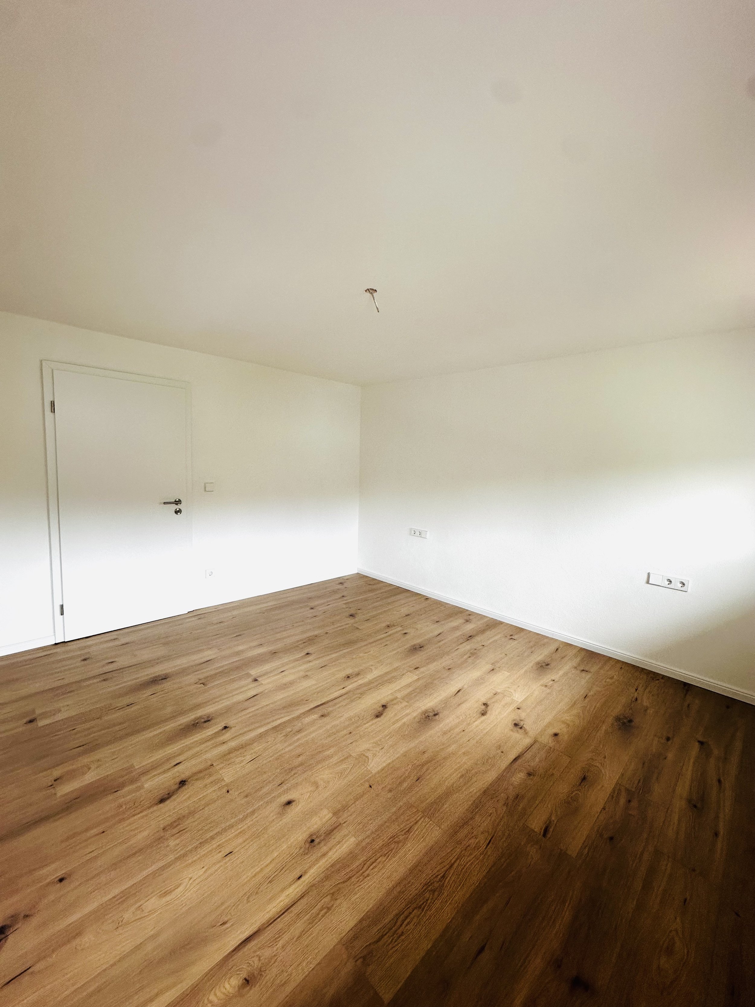 Helles Schlafzimmer mit verputzten Wänden und Eichen Laminat