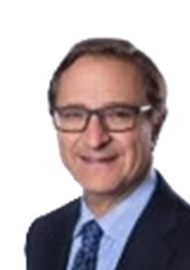 A middle-aged man with glasses, wearing a dark suit, light blue shirt, and patterned tie, smiling against a white background.