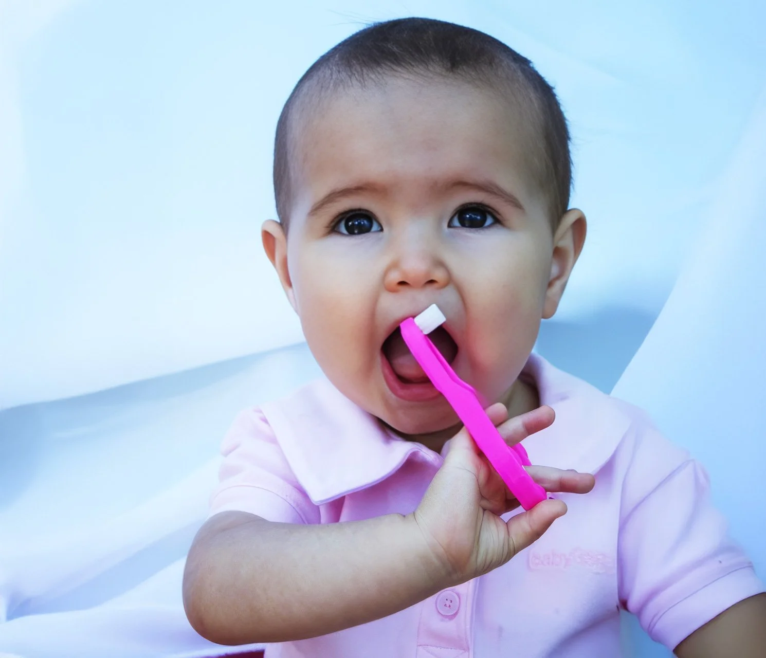 Baby holding a pink toothbrush