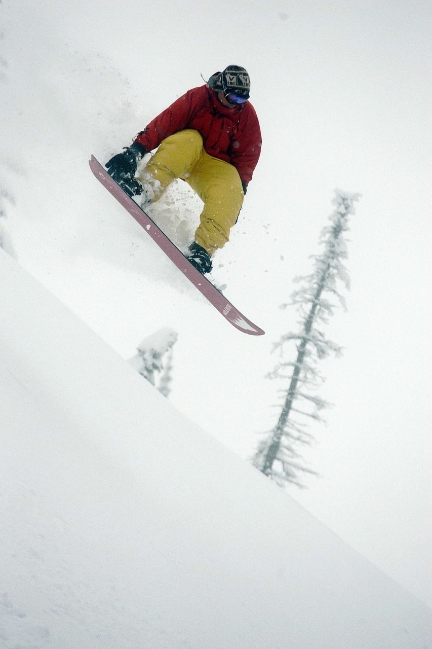 Dr. Ray in midair going off of a jump snowboarding