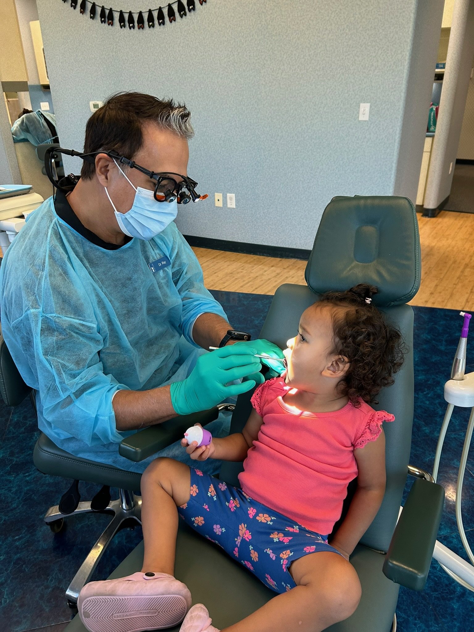 Dr. Ray checking a young toddler's teeth in the dental office