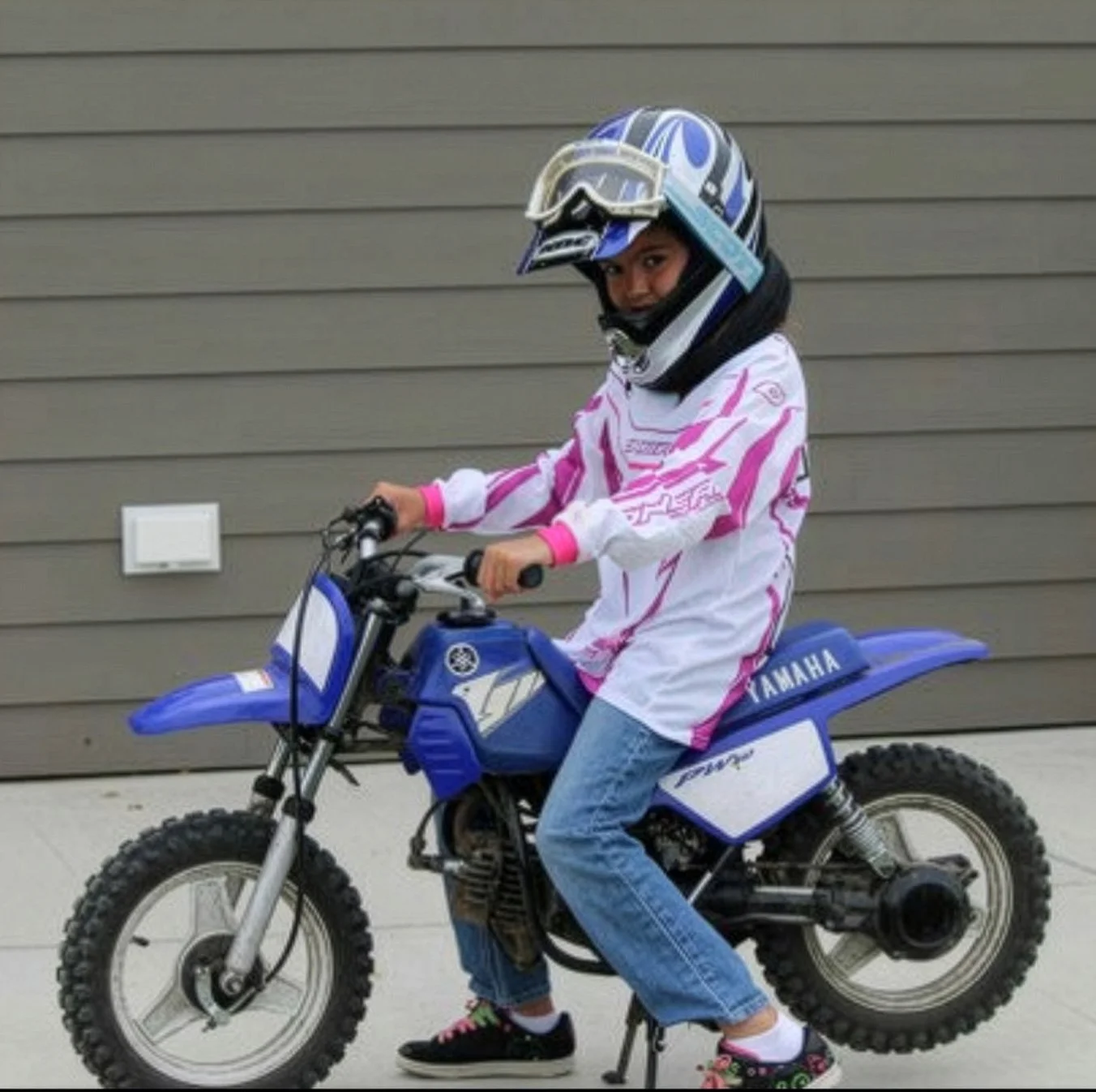 Young girl posing on a dirt bike wearing motorcycle riding gear