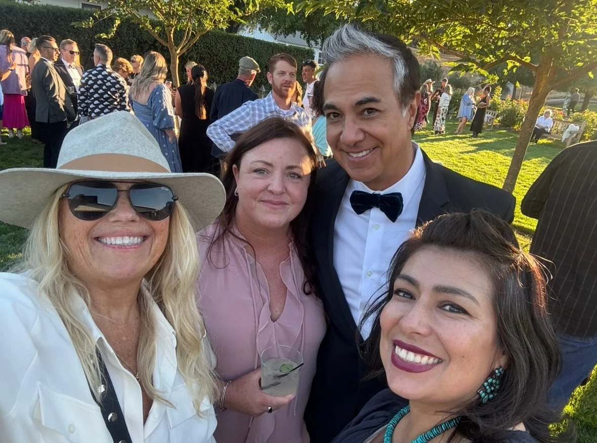 Four adults smiling for a selfie at an outdoor gathering