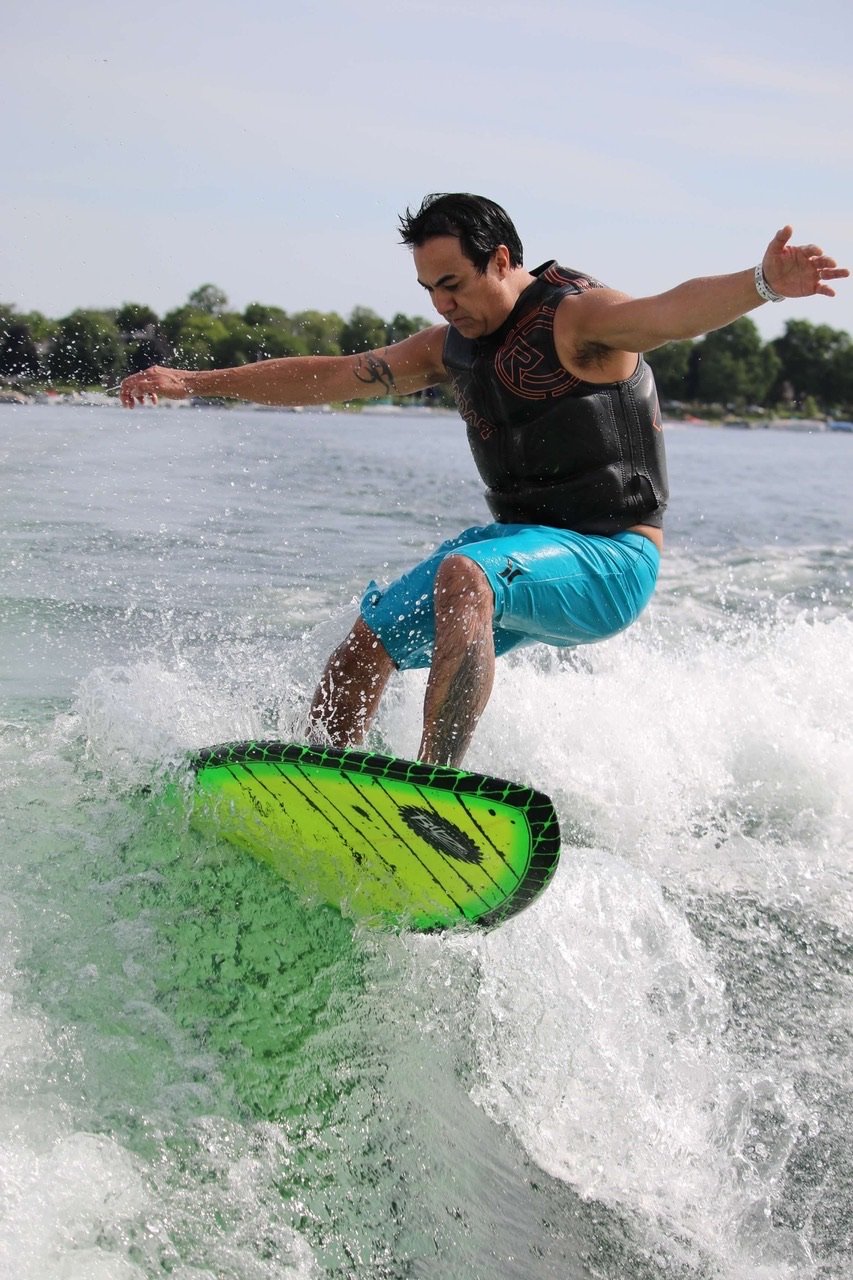 Dr. Ray surfing on a yellow surf board and blue trunks