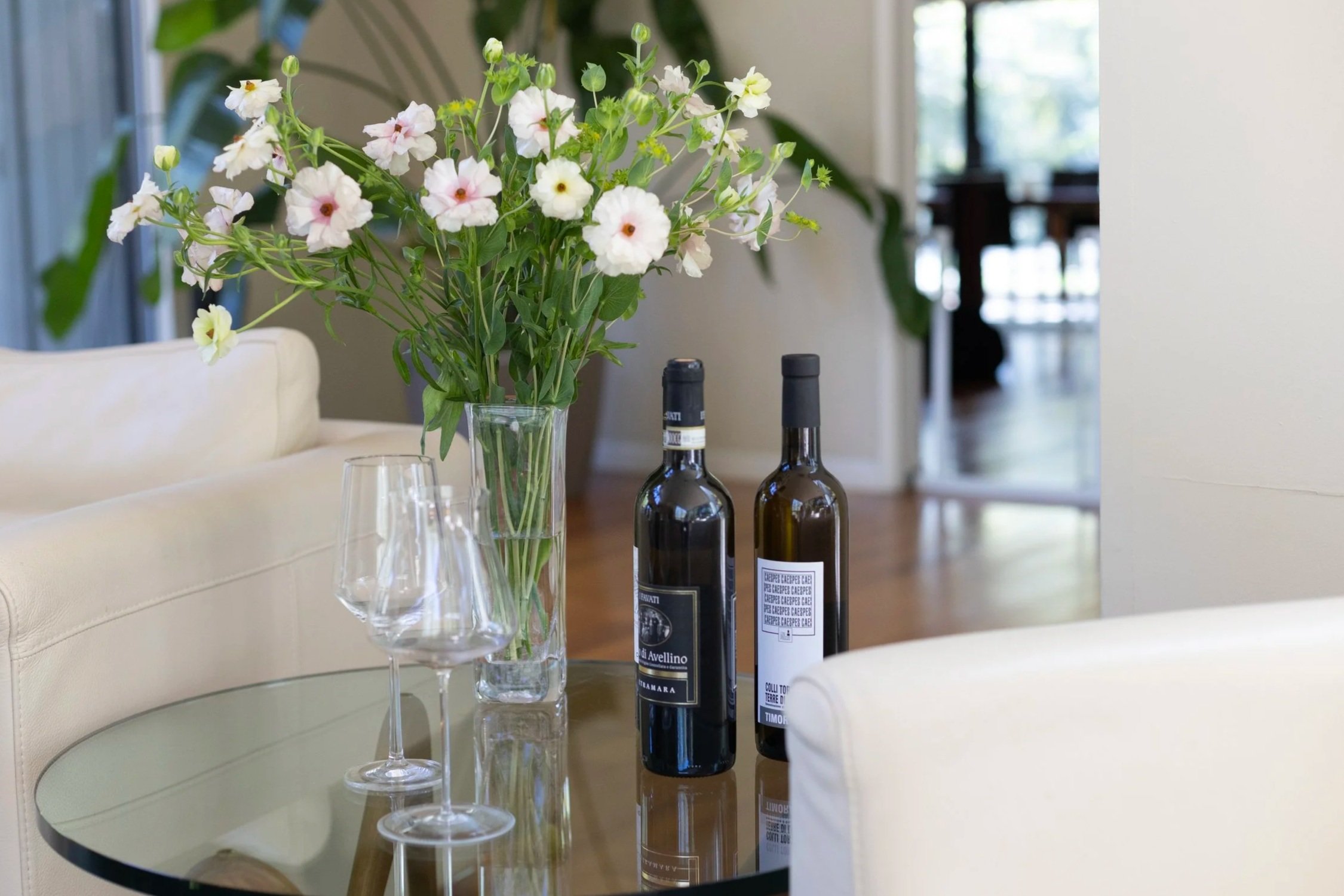A person holding a glass of wine at a wine tasting with a friend who holds another drink in the background.