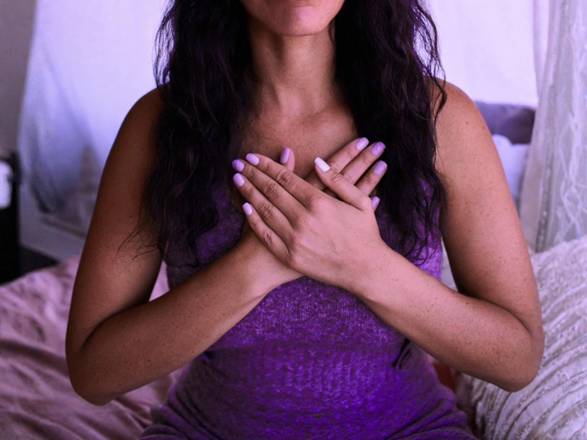 A woman practices self-reiki with her hands on her heart